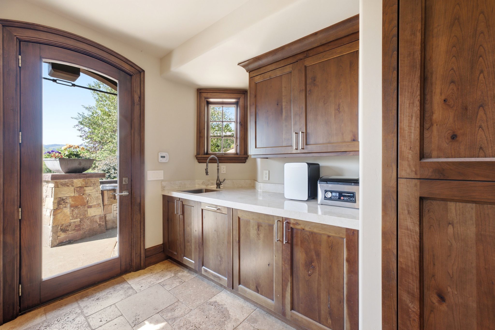 Kitchenette featuring wood-finish cabinetry, light-toned countertops, and a stainless steel sink with a gooseneck faucet
