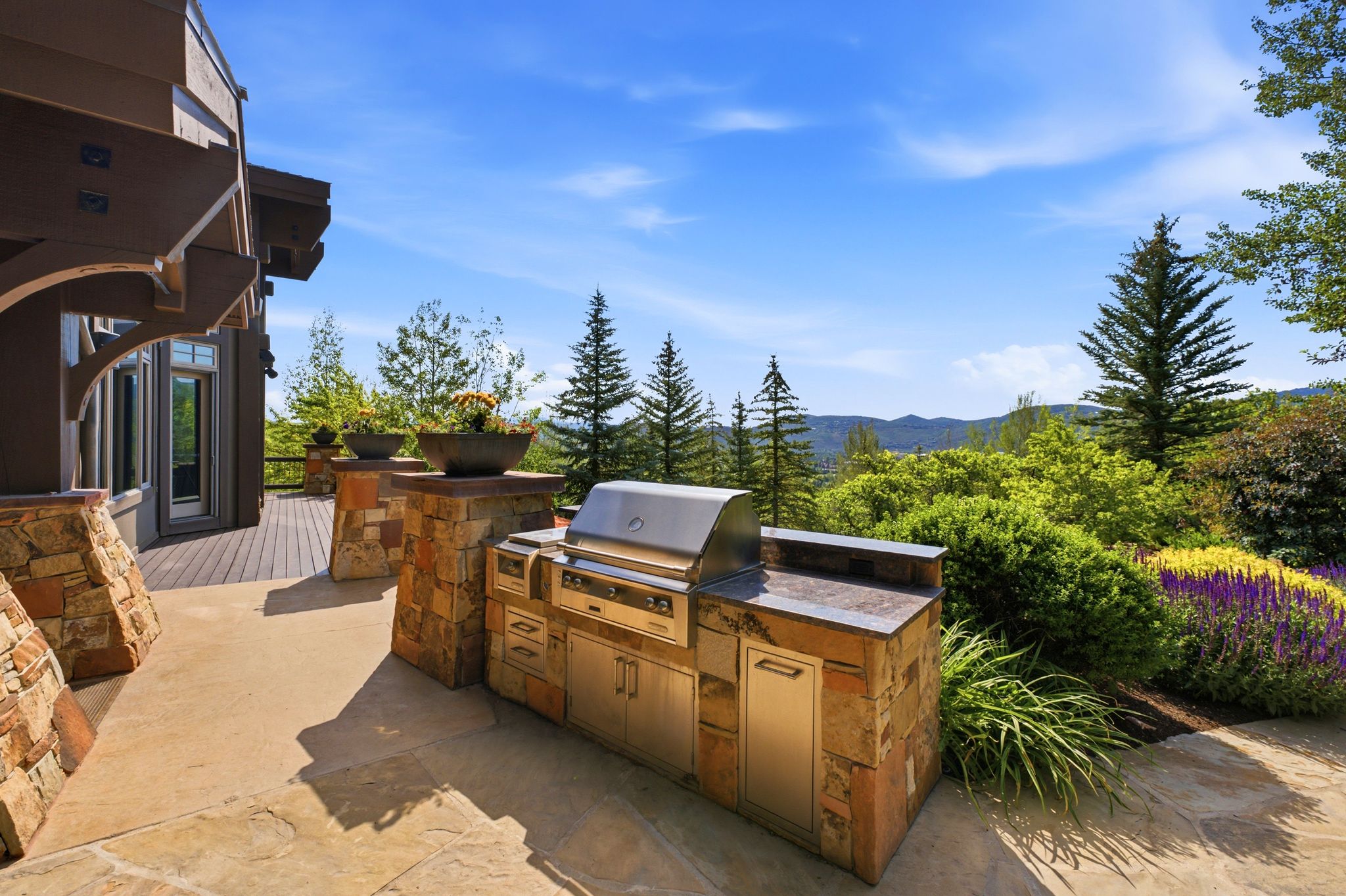 Outdoor kitchen featuring a built-in grill, stone veneer base, and dark countertop