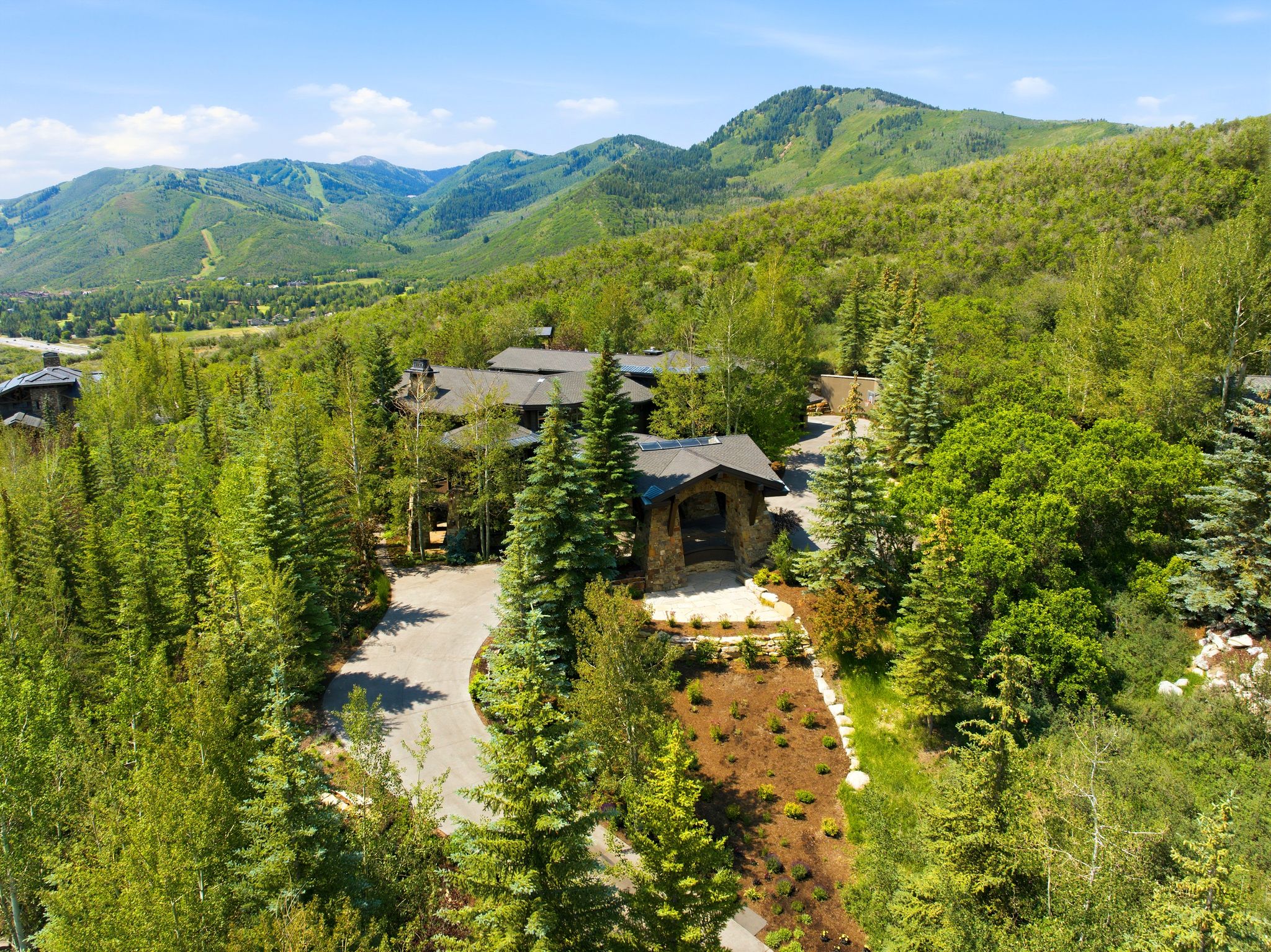 Stone-clad architectural style surrounded by mature evergreen and deciduous trees