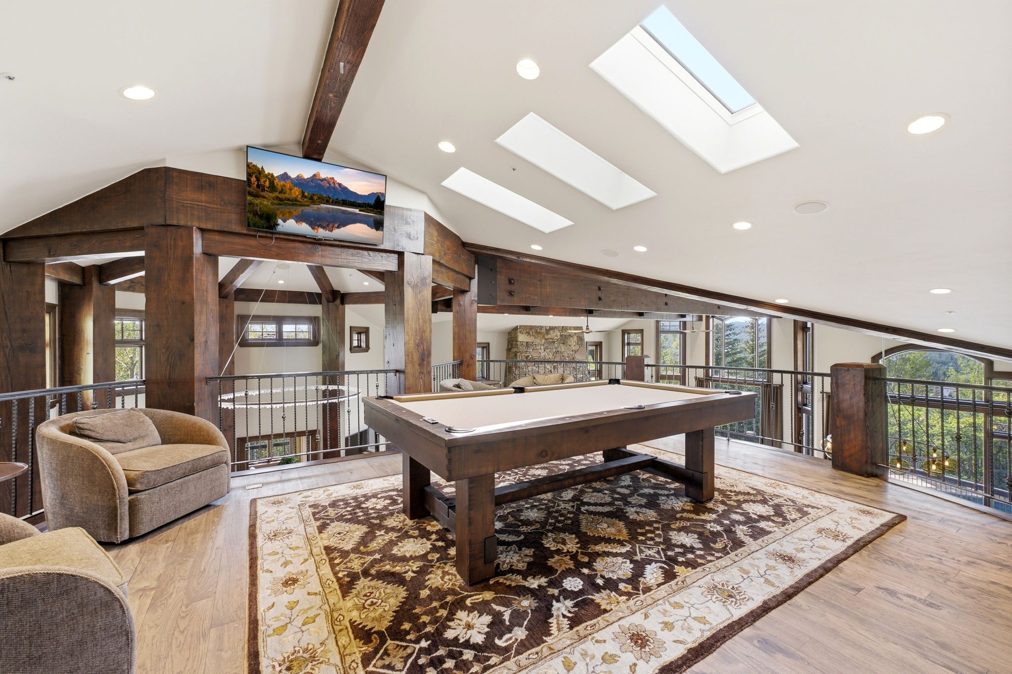 Spacious loft area featuring a billiard table, wood-finish flooring, and exposed timber beams