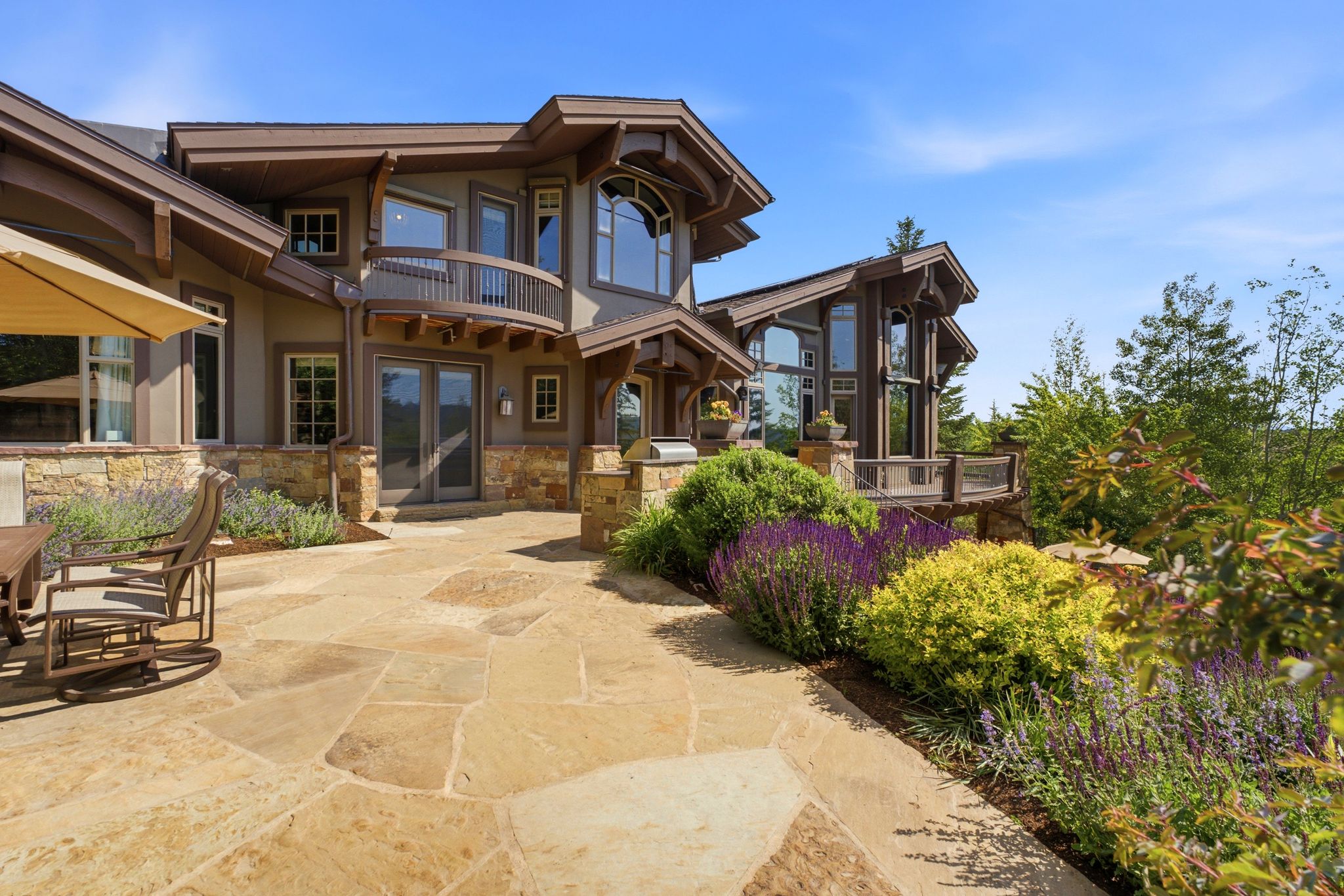 Expansive flagstone patio with surrounding landscaping and a stone-clad exterior