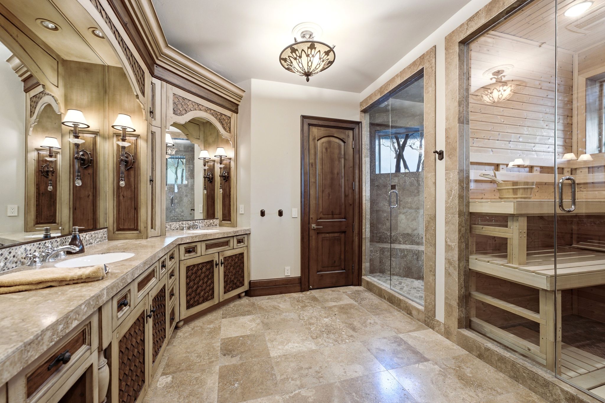 Spa-inspired bathroom featuring a glass-enclosed sauna, glass-enclosed shower with tile surround, and a double vanity with integrated sinks