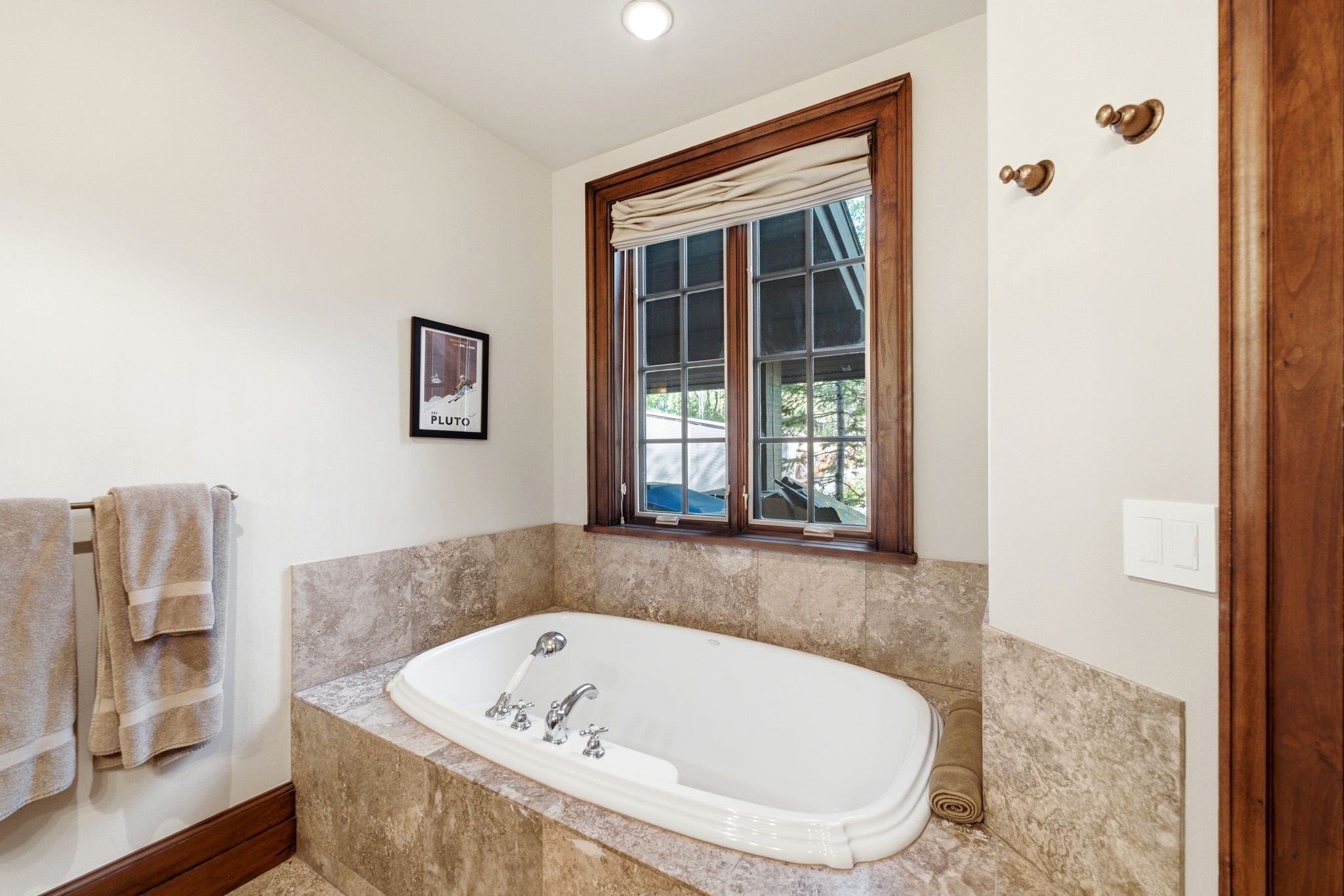 Built-in soaking tub with deck-mounted fixtures, surrounded by natural stone tiling