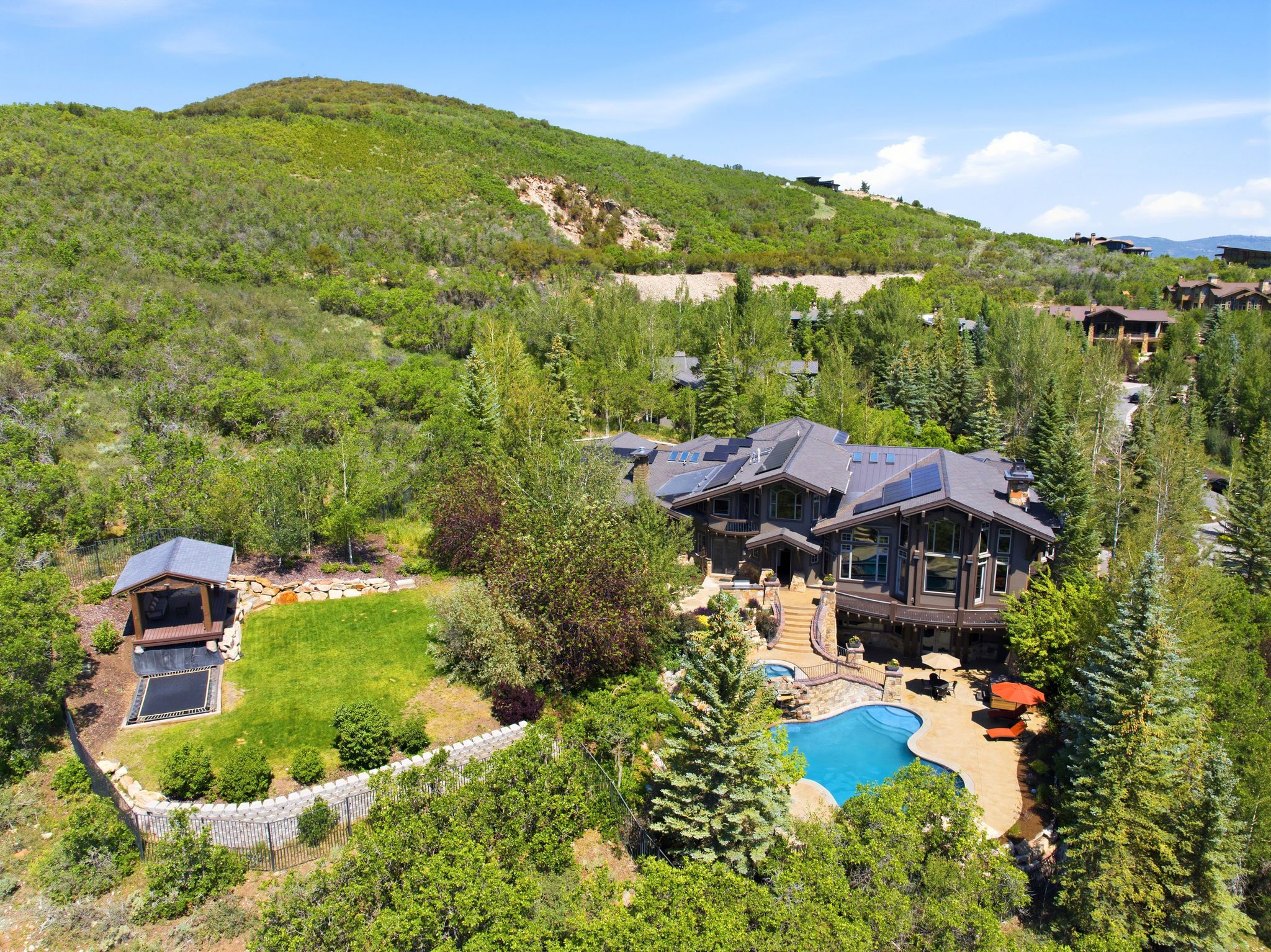 Mountain-style residence featuring a multi-level exterior, an outdoor swimming pool, and a stone patio