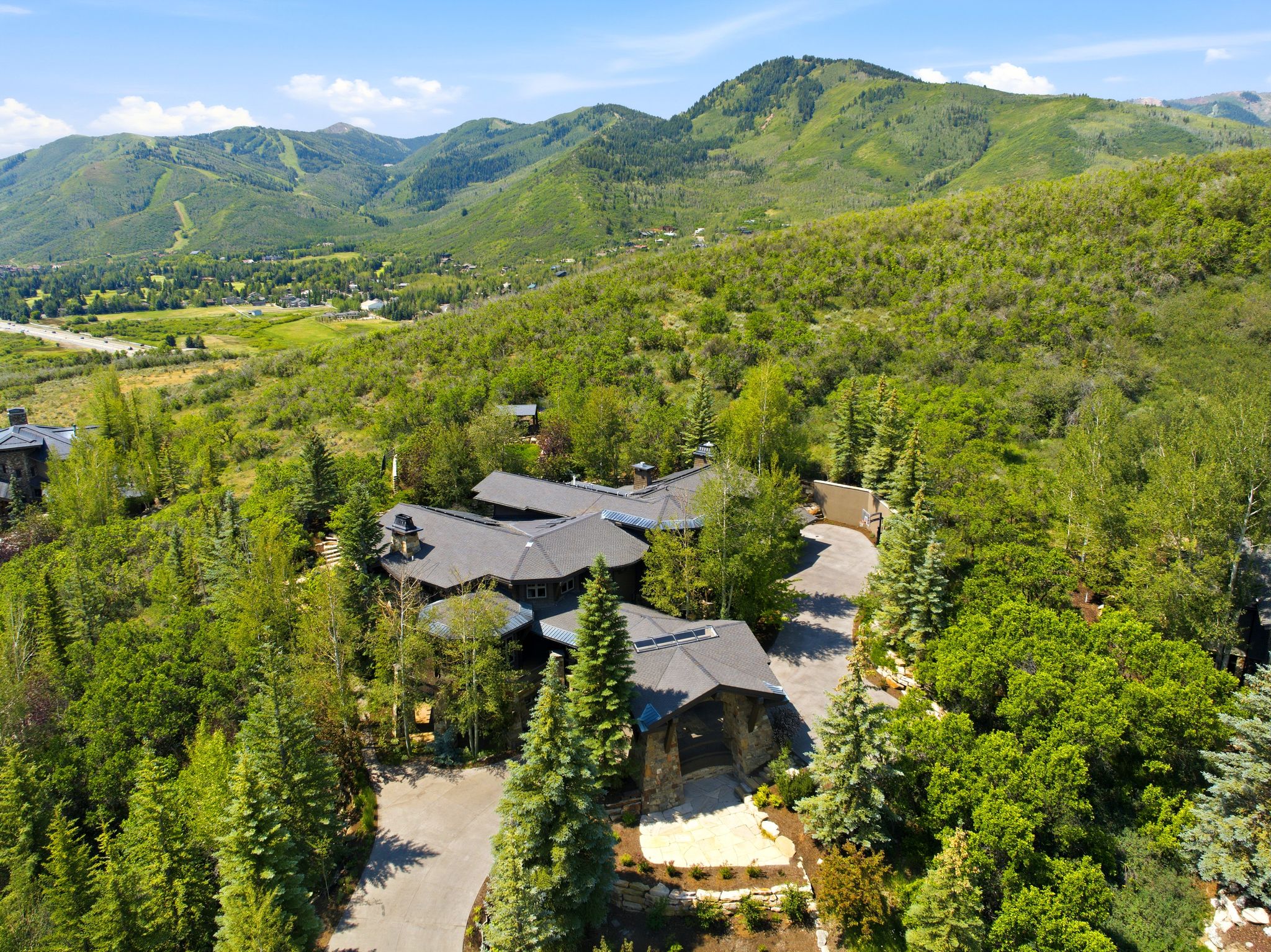 Expansive mountain property featuring a large residence with multiple rooflines, a paved driveway, and mature trees