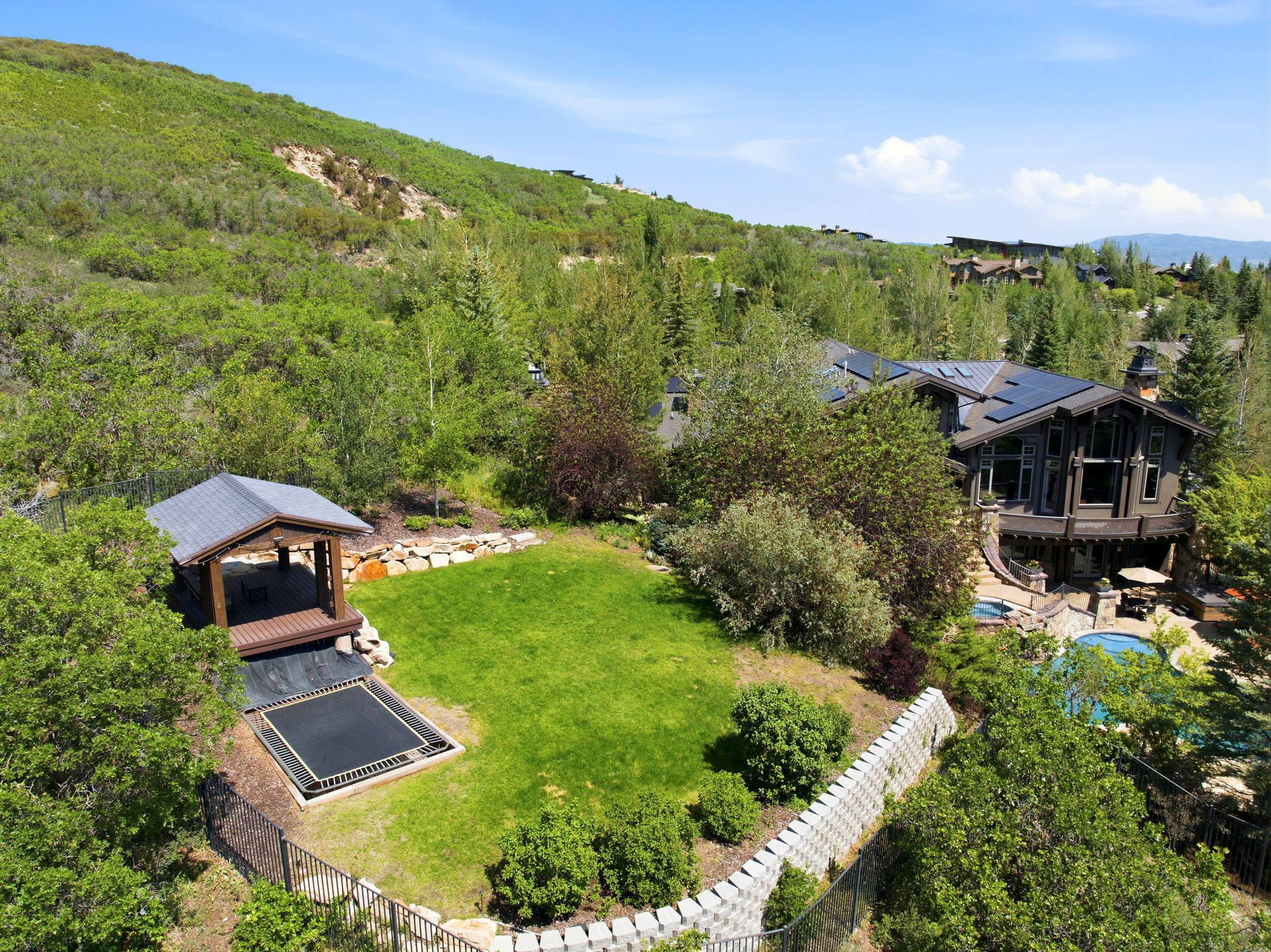 Expansive terraced yard with a built-in trampoline, covered gazebo, and manicured lawn