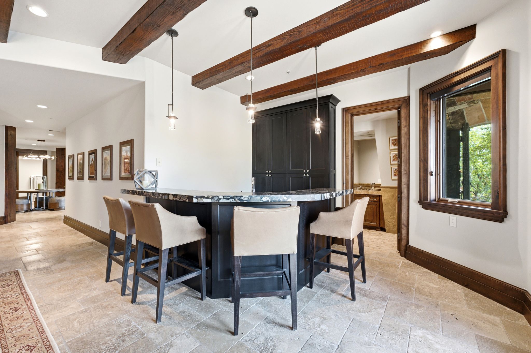 Wet bar featuring dark wood cabinetry, a stone countertop, and three pendant lights