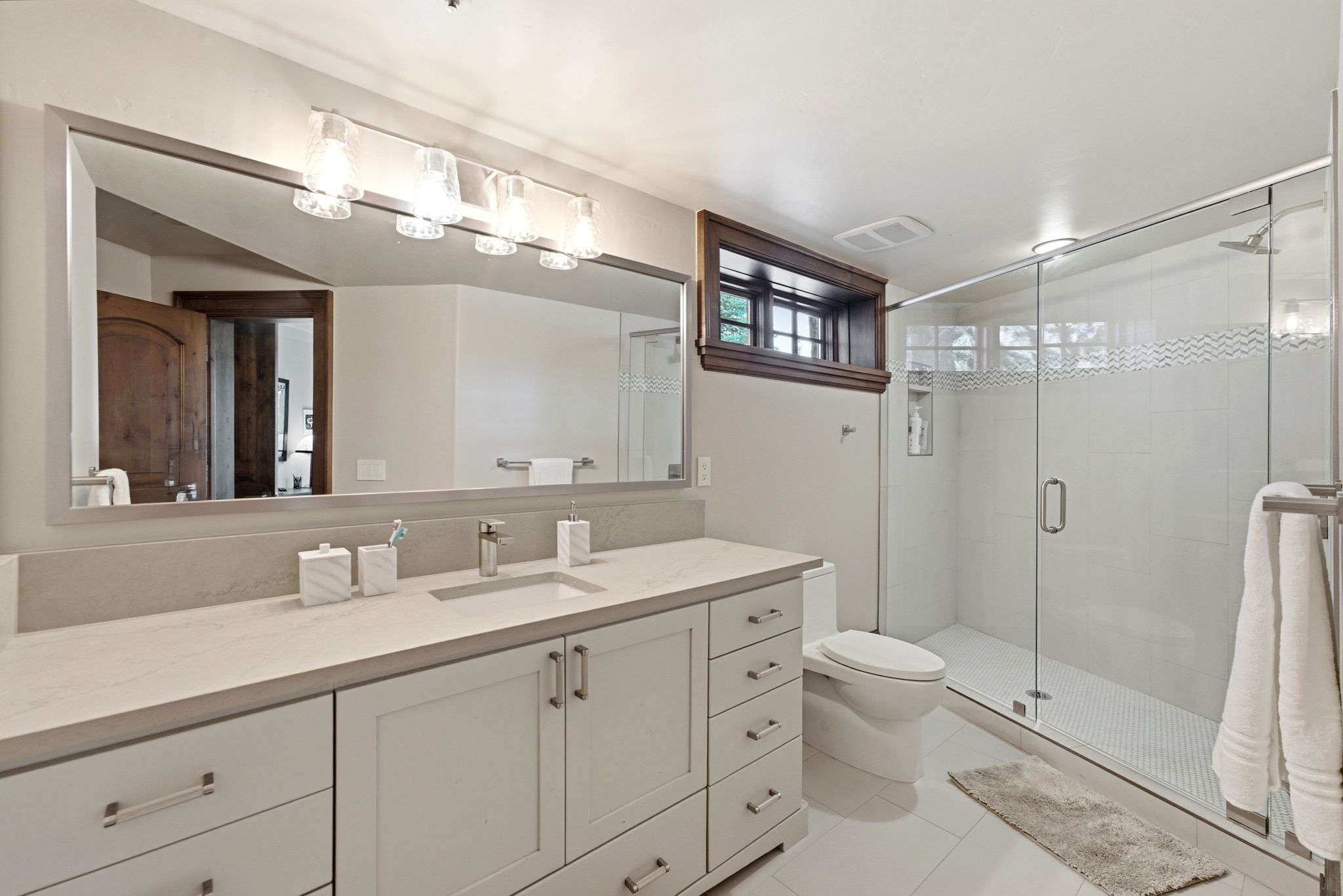Contemporary bathroom featuring a spacious glass-enclosed shower with white subway tile and a decorative wave accent
