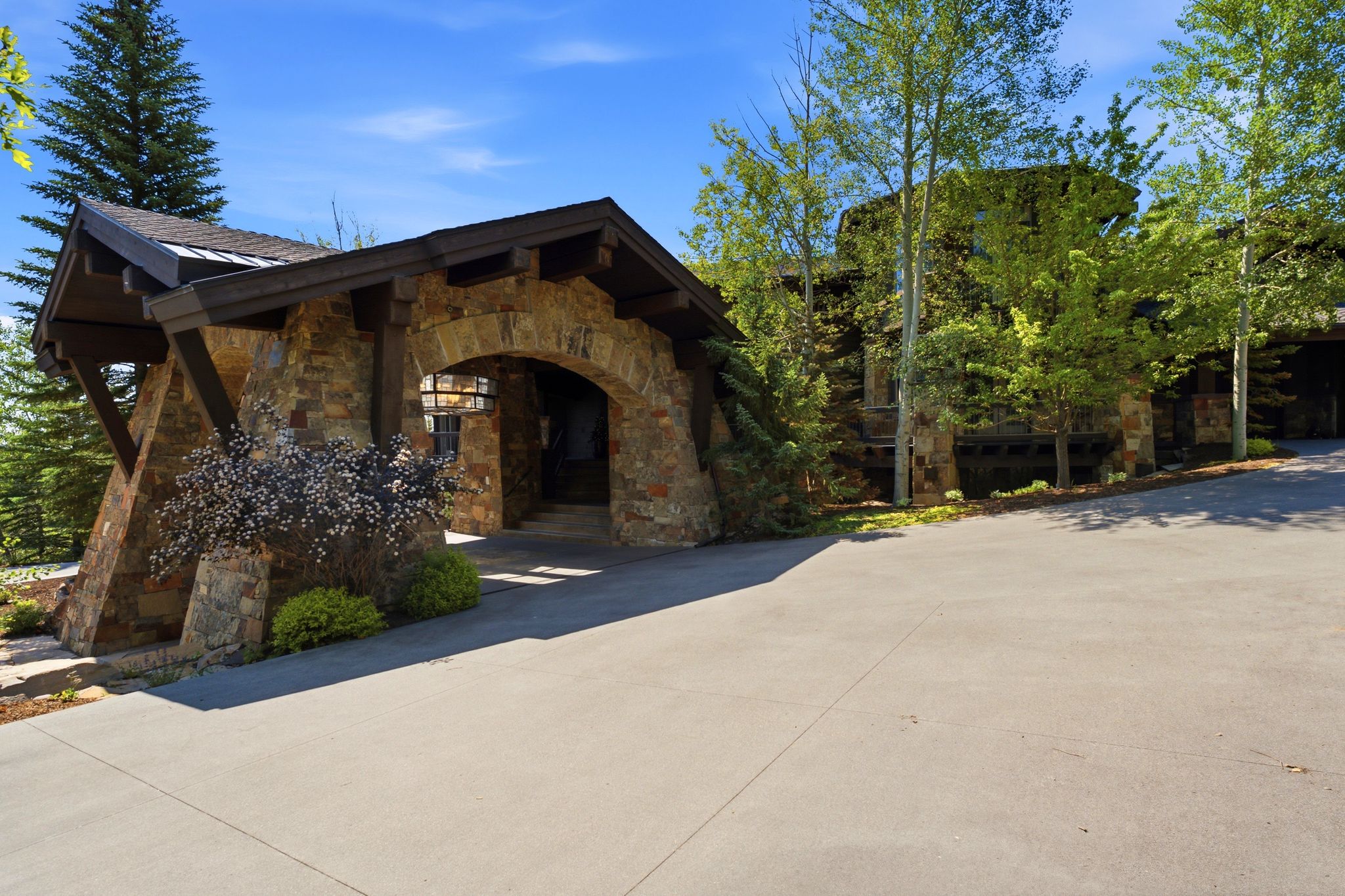Stone porte-cochere entry with dark wood accents and an arched doorway
