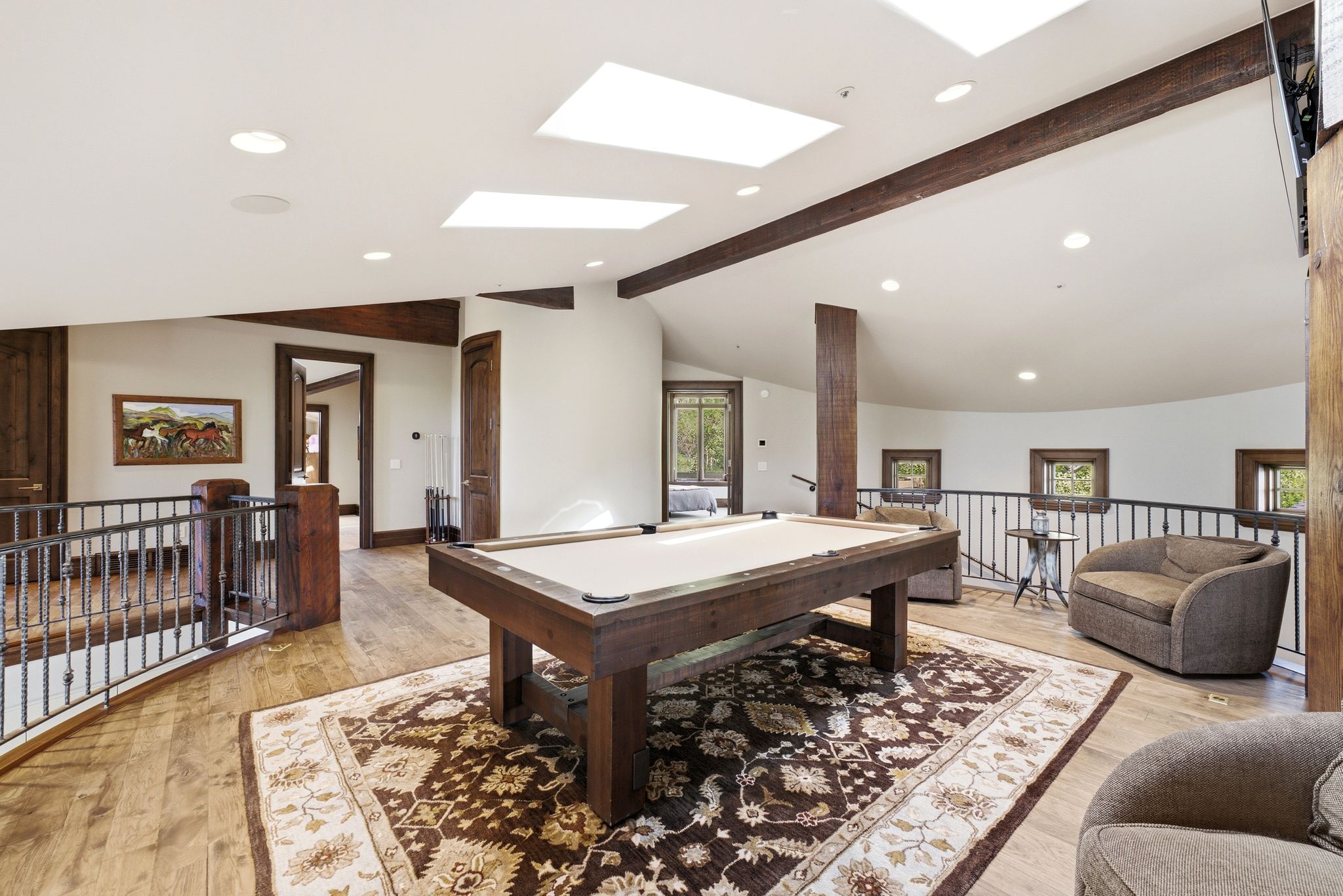 Spacious upper-level area featuring wood-finish flooring, exposed wood beams, and recessed lighting