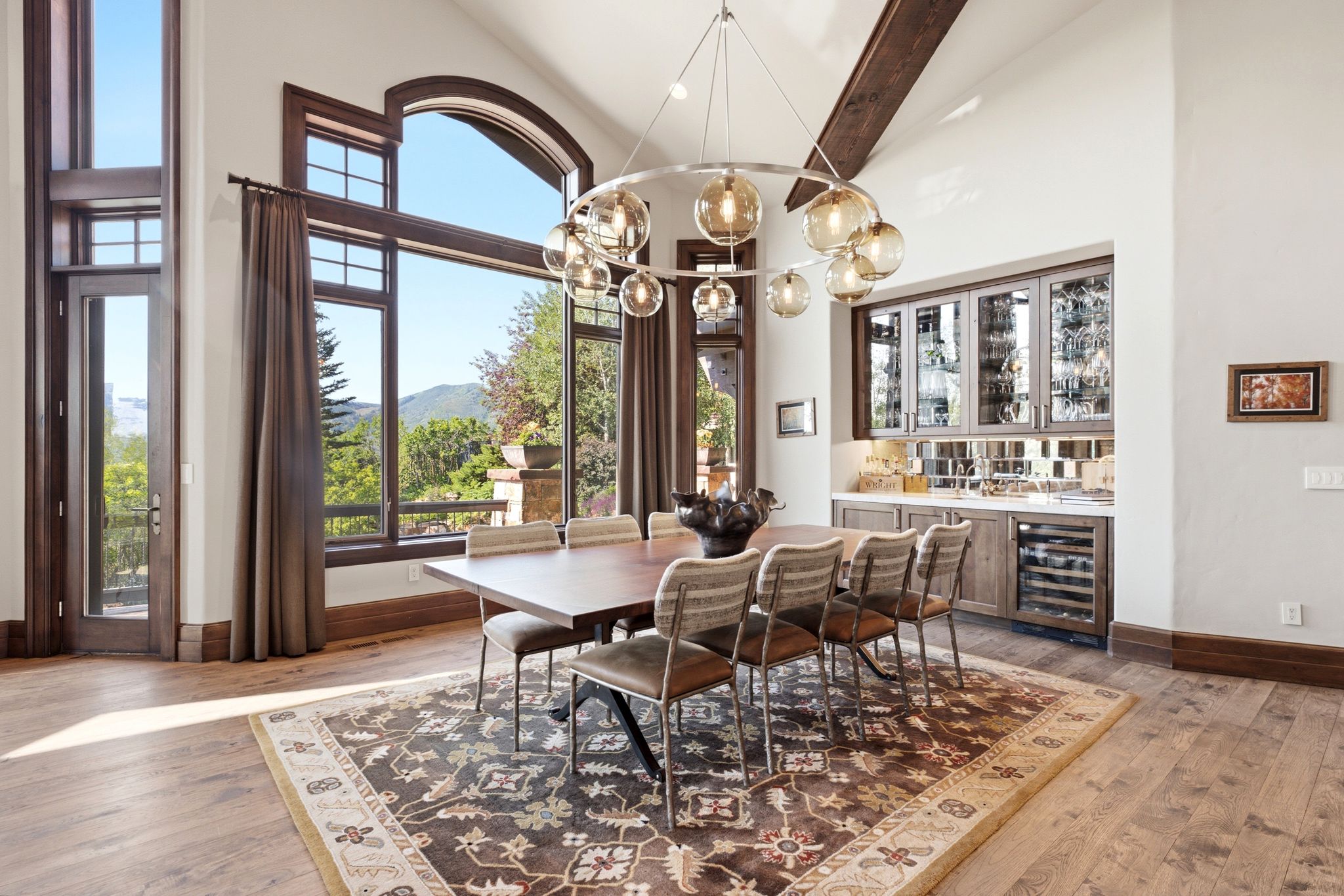 Dining area featuring a vaulted ceiling with exposed wood beams, extensive window framing, and wood-finish flooring