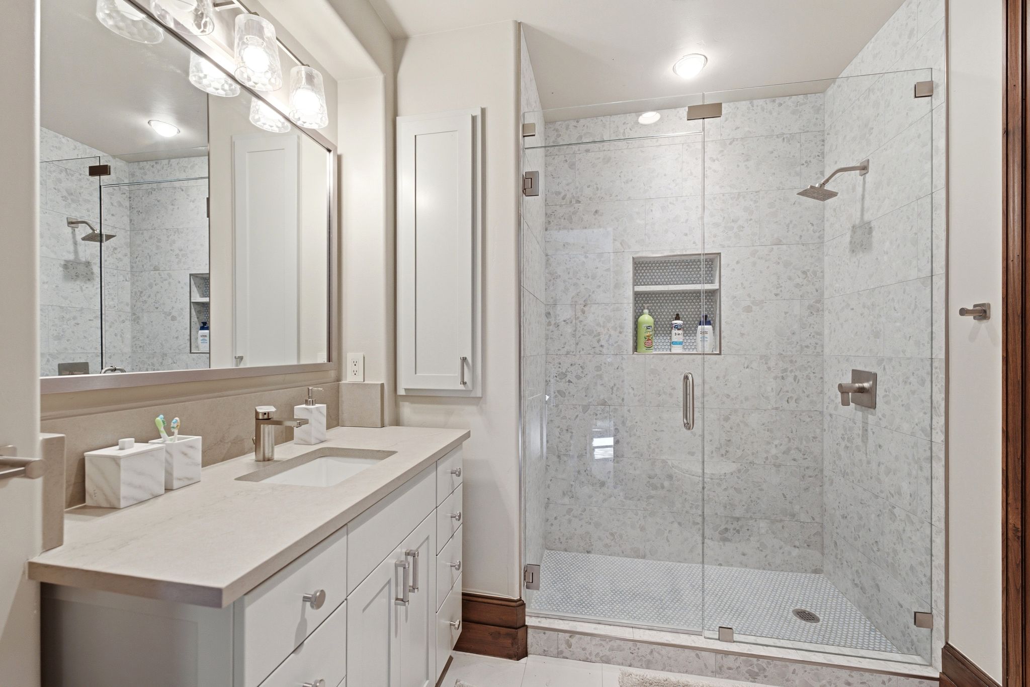 Spacious bathroom featuring a glass-enclosed shower with white tiled walls and a recessed niche