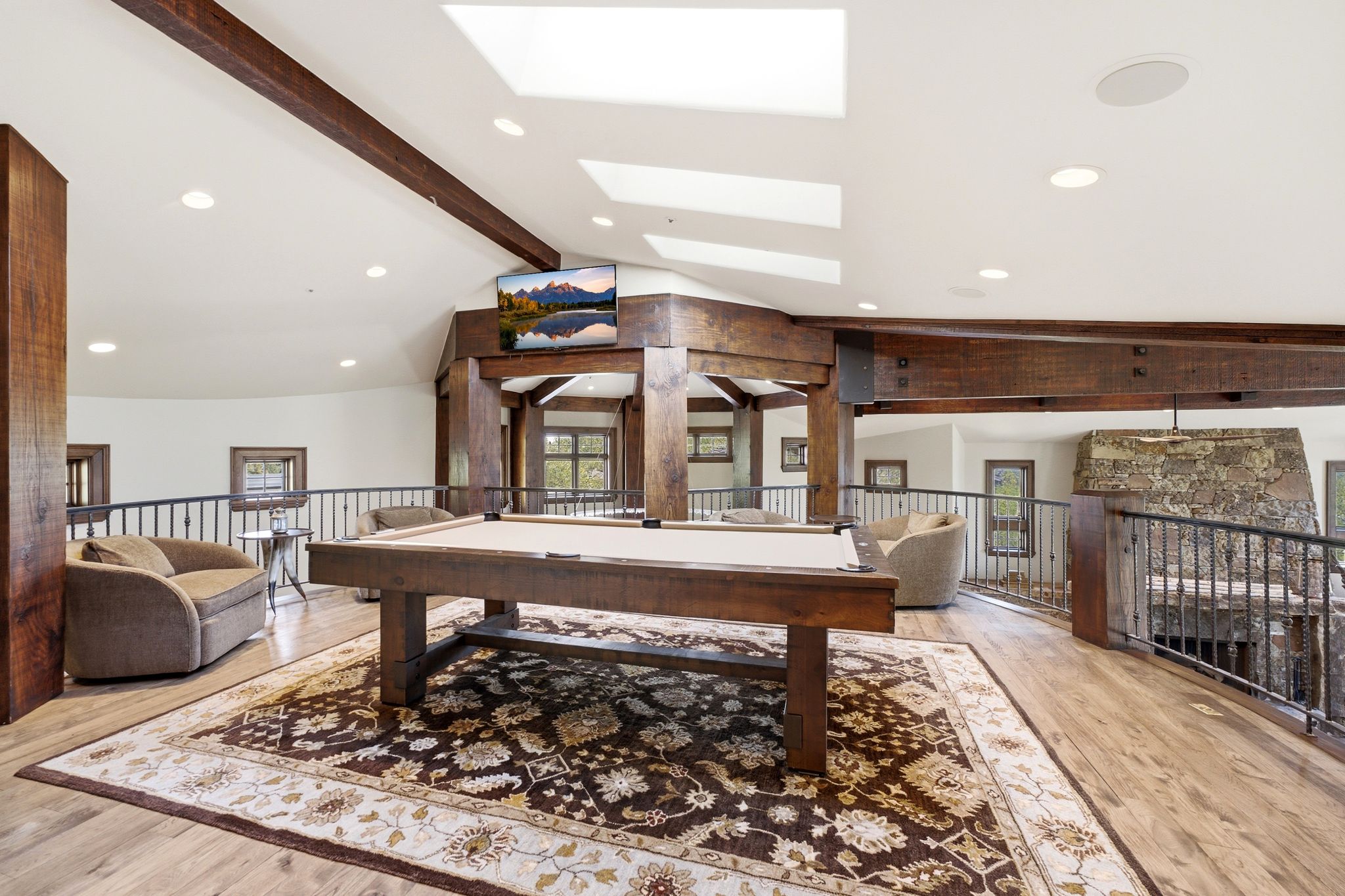 Open loft area featuring exposed wood beams and a large area rug