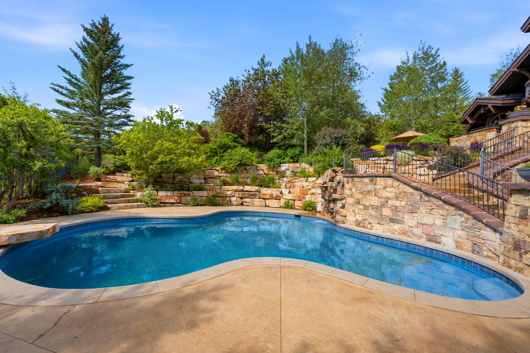 Freeform swimming pool featuring a natural rock waterfall and integrated diving platform