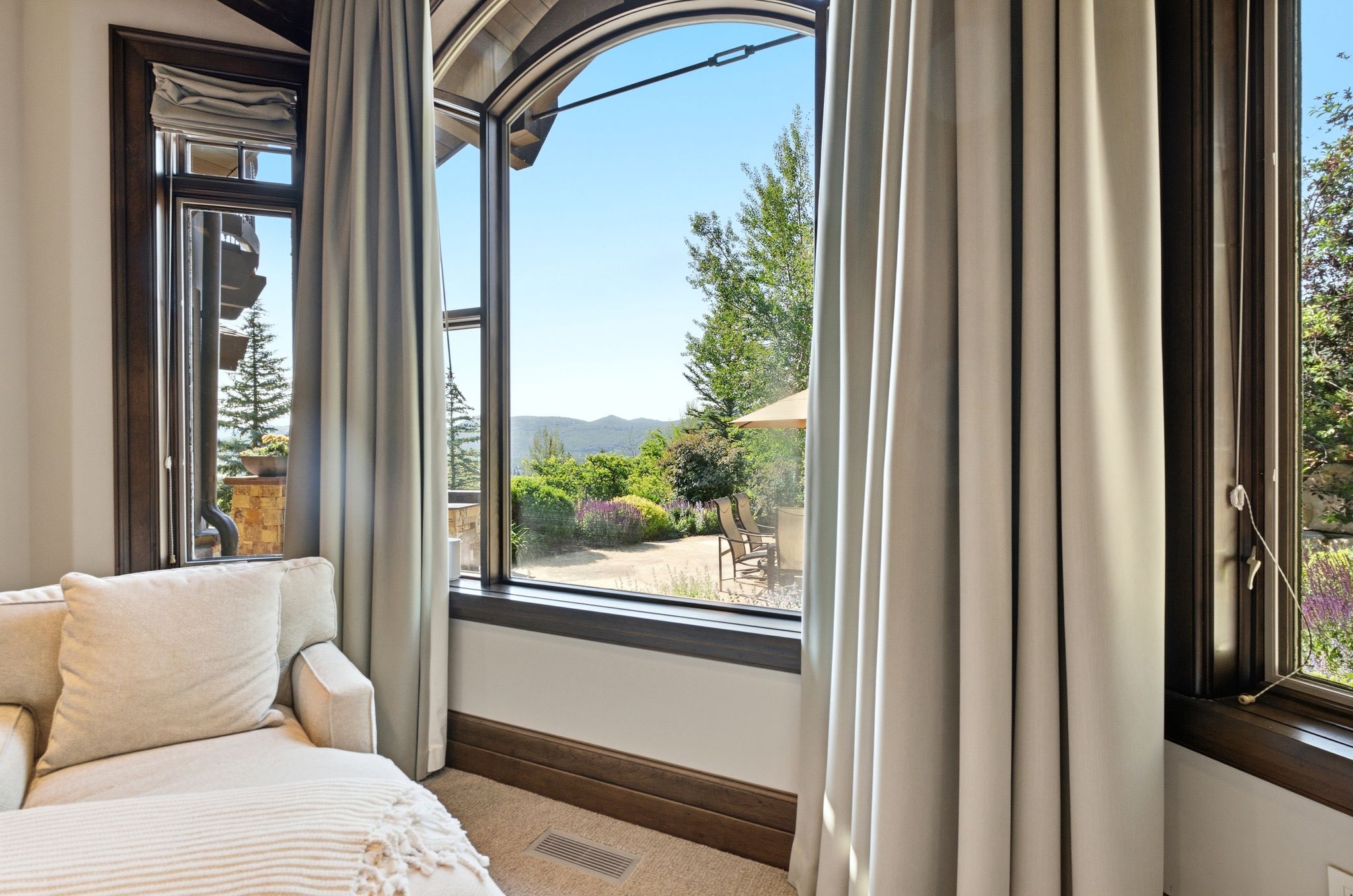 Arch-top window with dark wood trim, framing a distant mountain landscape