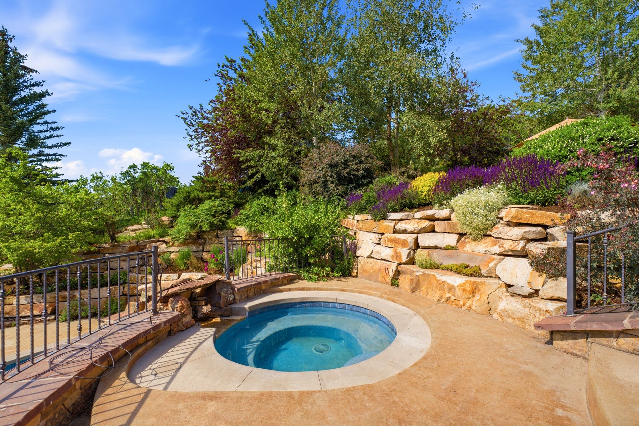 Outdoor spa with surrounding hardscaping, a stone retaining wall, and diverse plantings