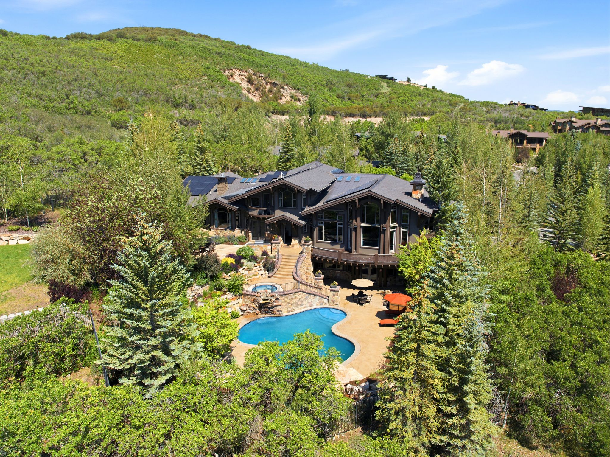 Spacious residence featuring a multi-level deck, a curved swimming pool, and an integrated hot tub