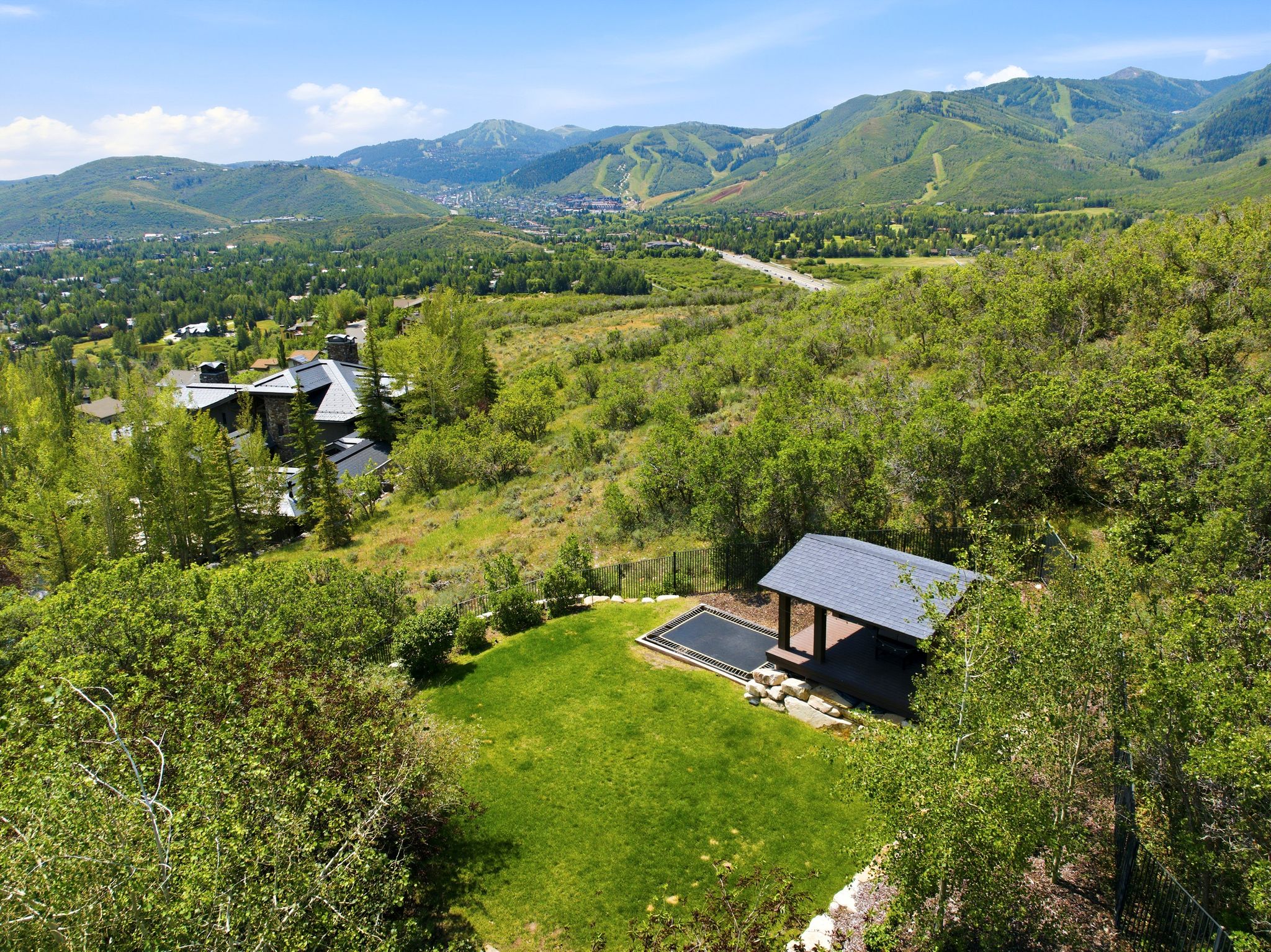 Expansive grounds featuring a manicured lawn area, a covered outdoor structure with a dark-tiled roof, and an adjacent dark-bottomed pool