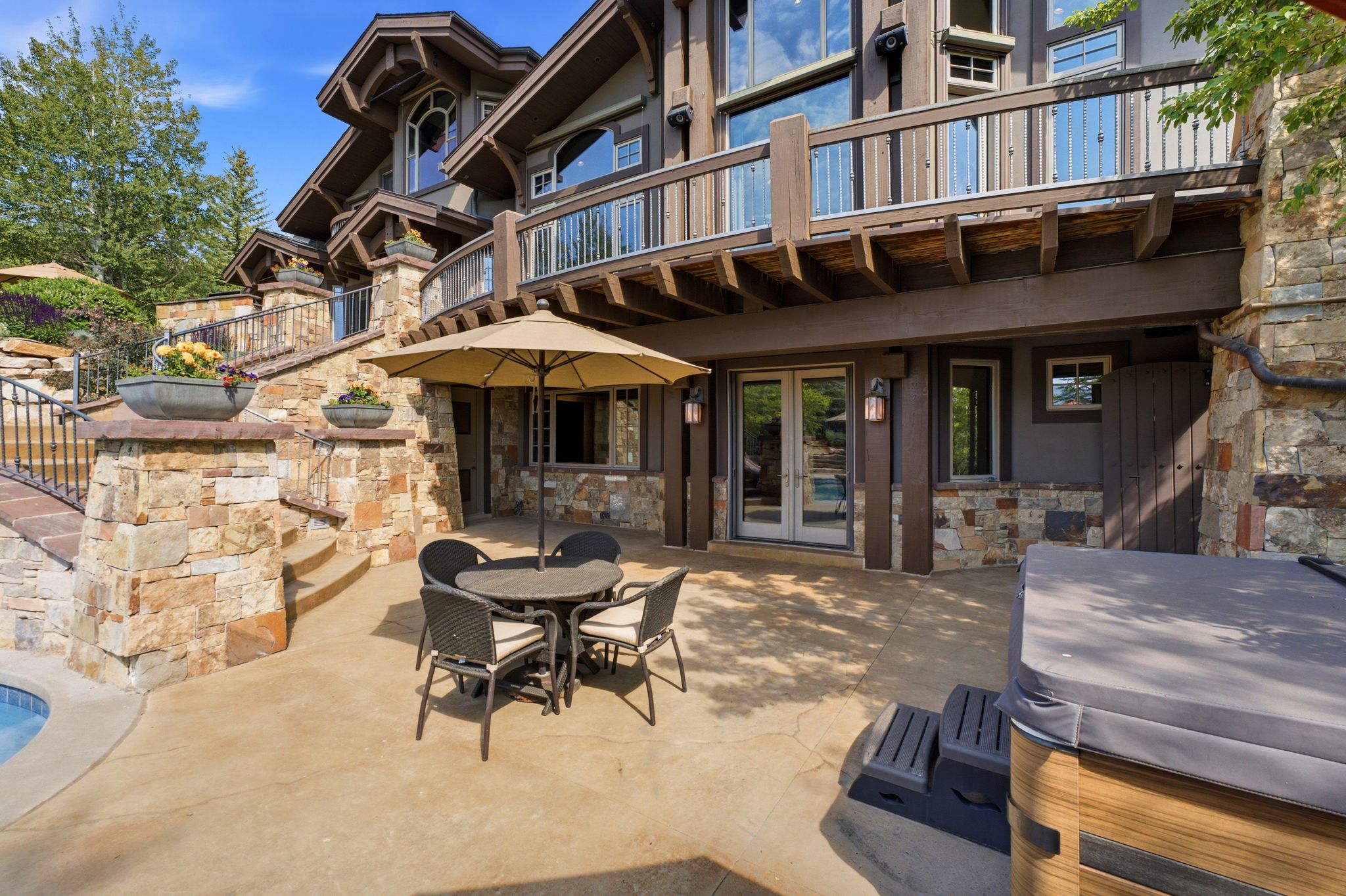 Expansive outdoor patio featuring a hot tub, a built-in pool, and a stone retaining wall with integrated planters