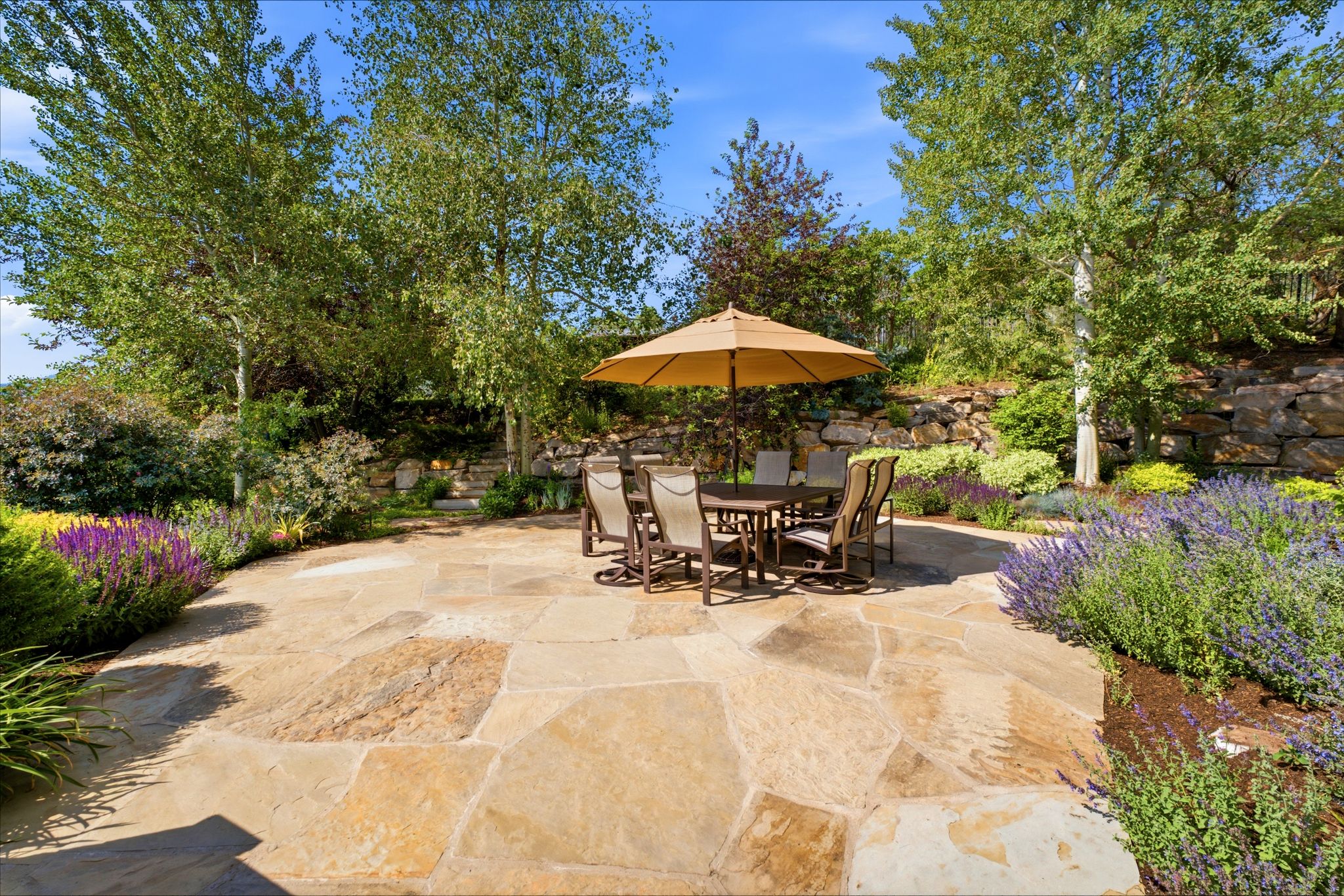Expansive flagstone patio with surrounding mature trees and lush landscaping