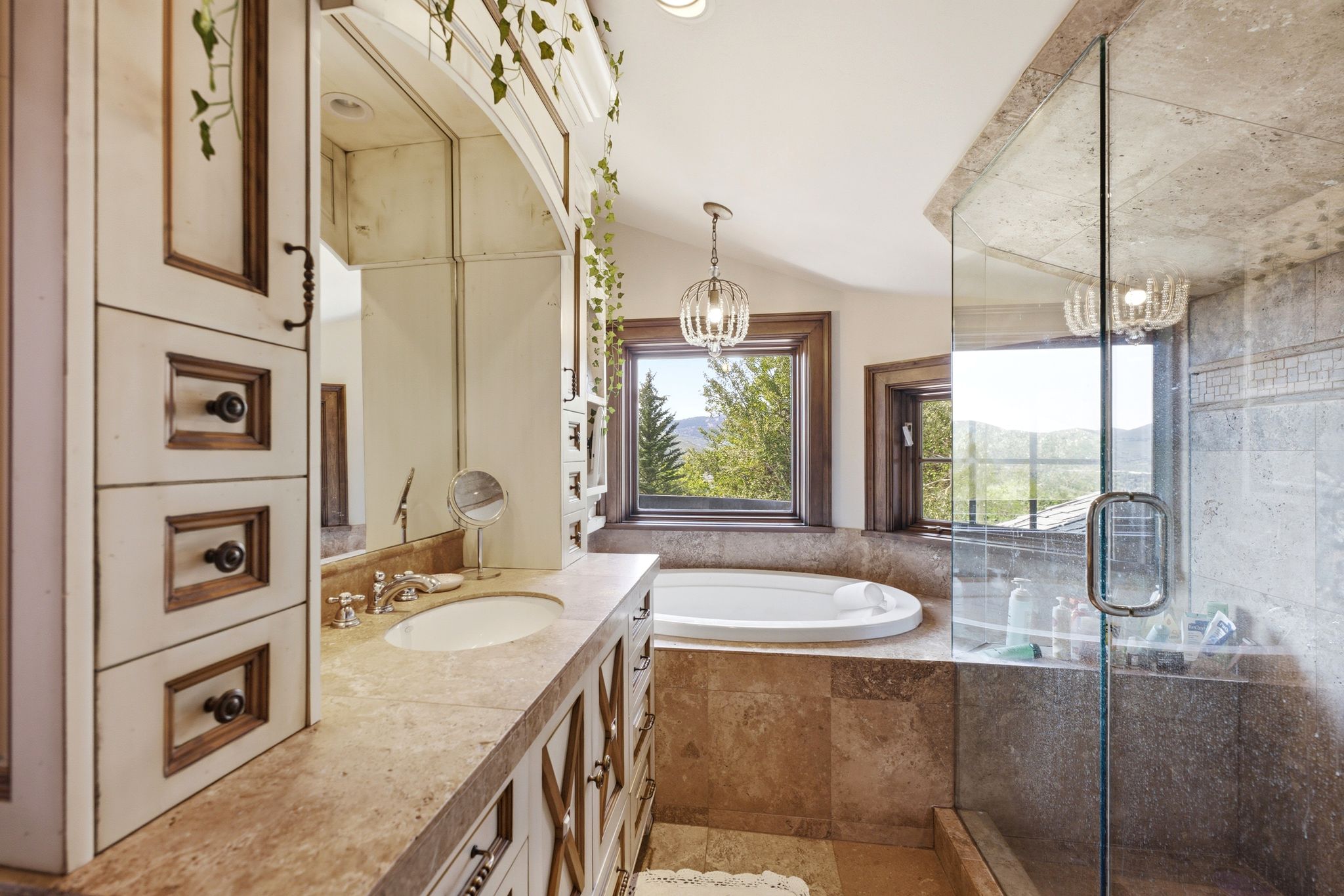 Bathroom featuring a large soaking tub, glass-enclosed shower, stone-finish countertops, and custom cabinetry with dark hardware