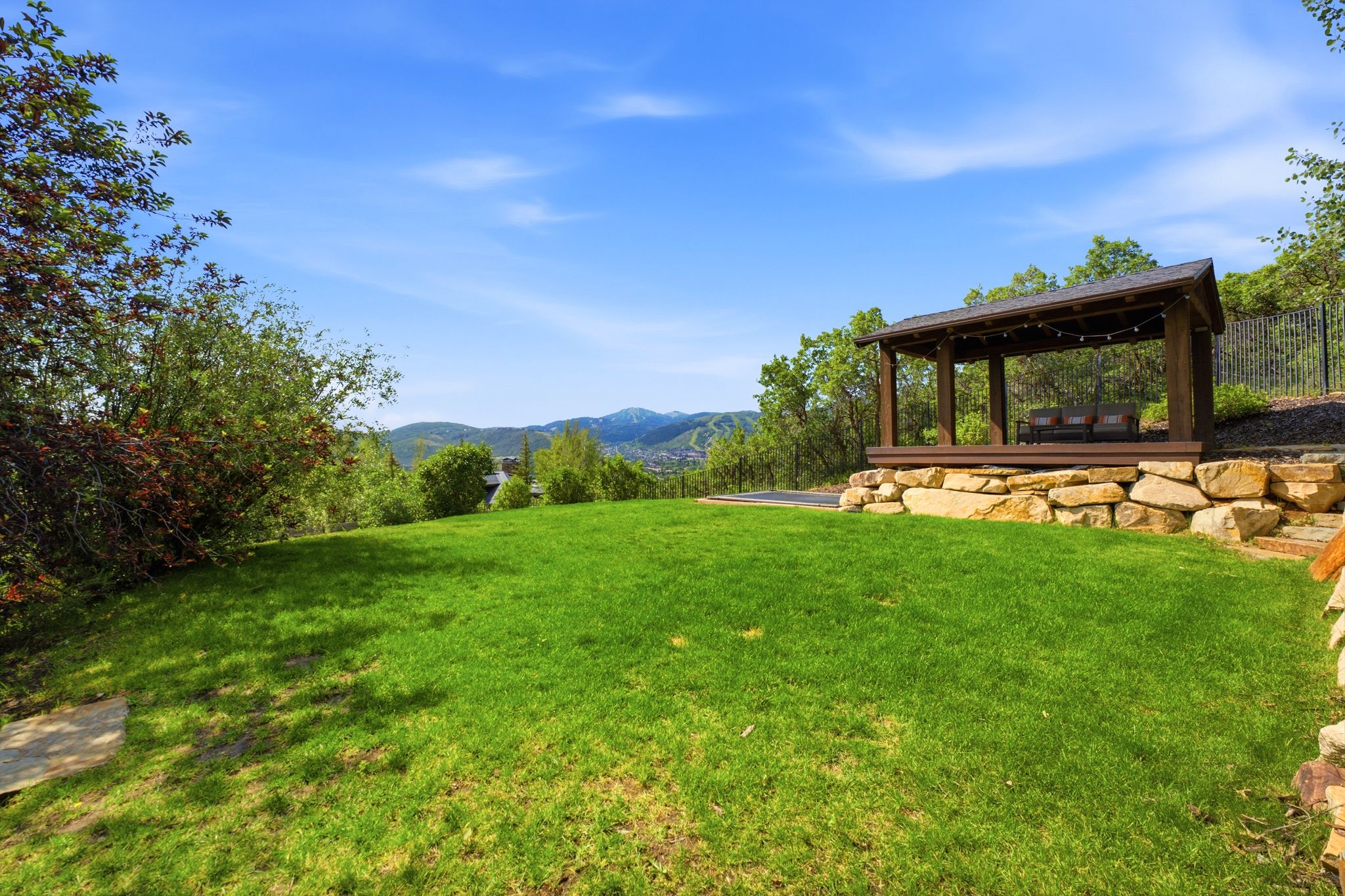 Expansive lawn with a wooden gazebo and stone retaining wall