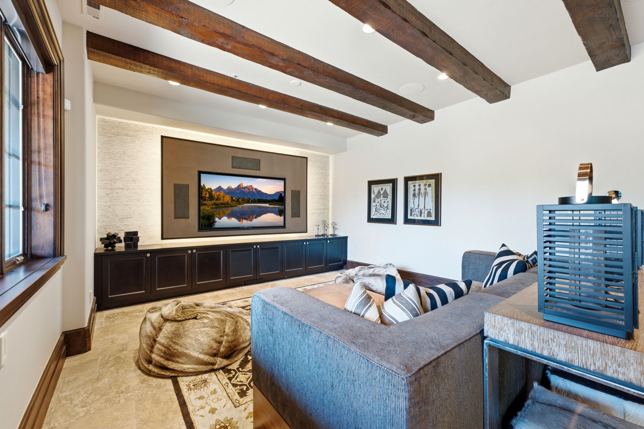 Entertainment space featuring a large built-in media console with integrated speakers, recessed wall lighting, and dark wood-finish cabinetry