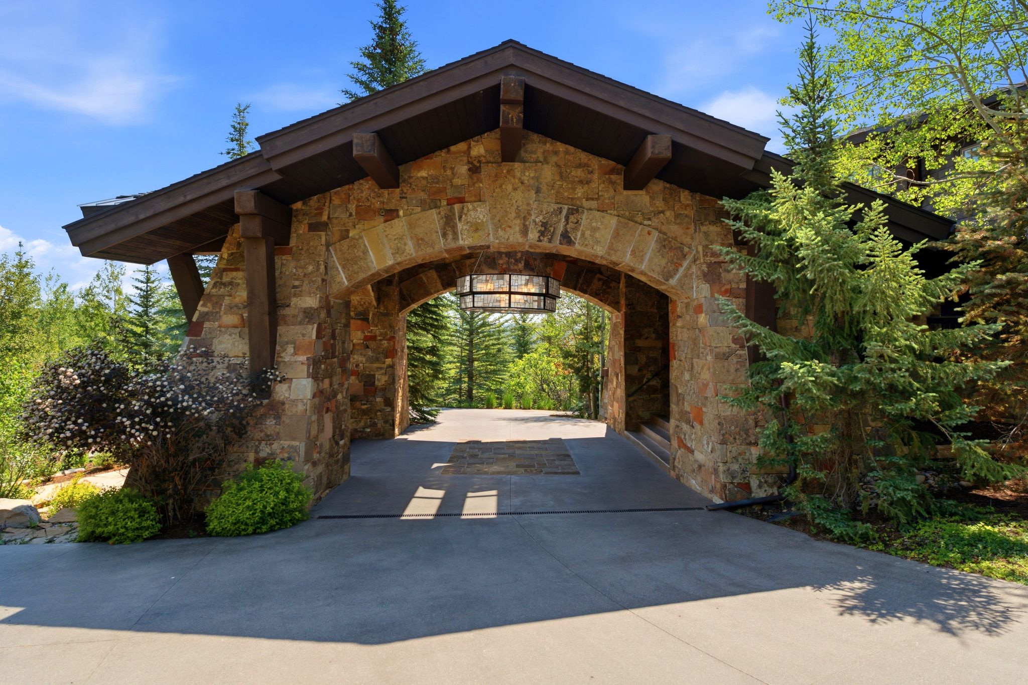 Stone archway entry featuring a concrete driveway and exposed timber beams