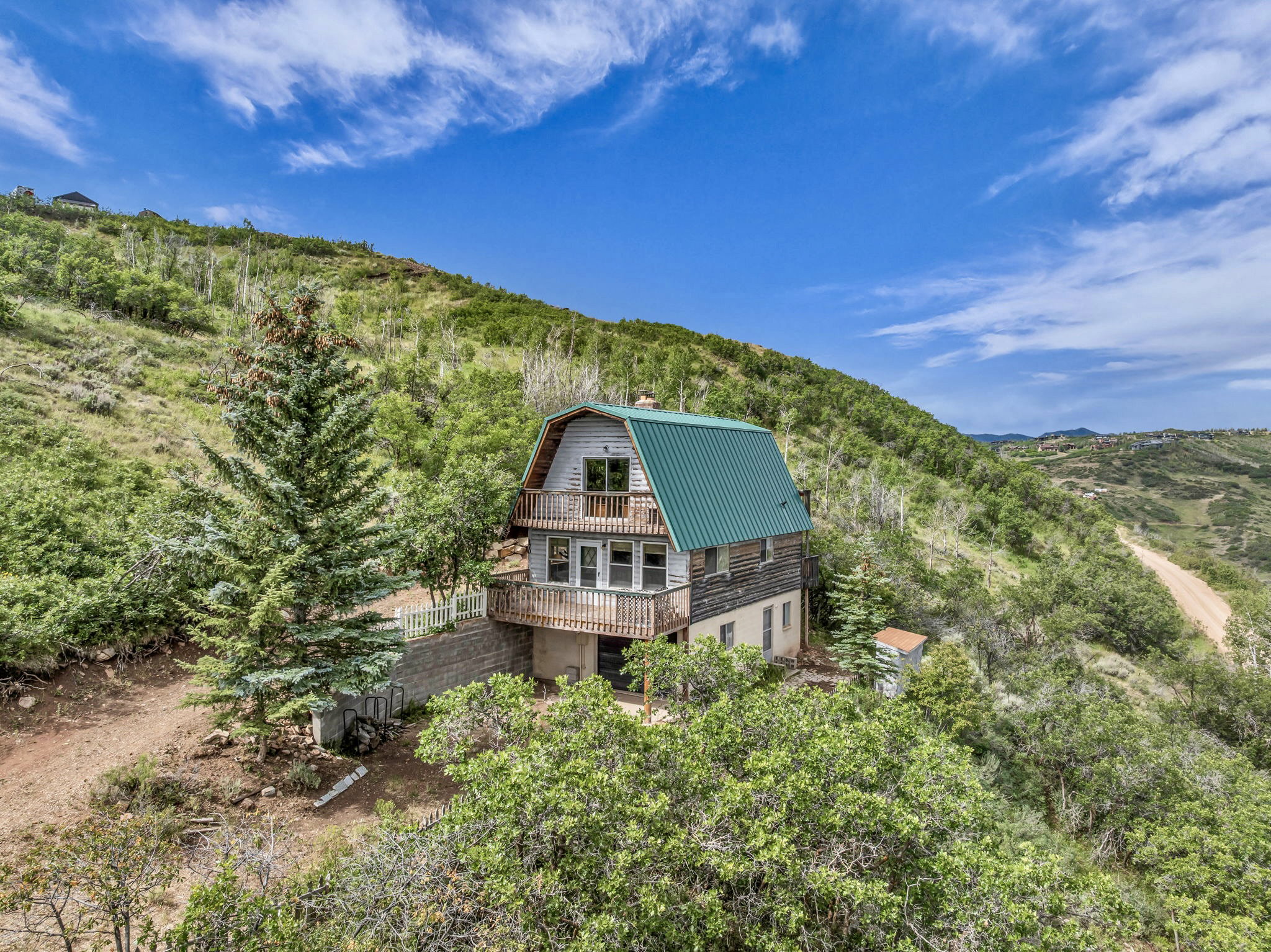 A green metal gable roof, nestled on the hill top.