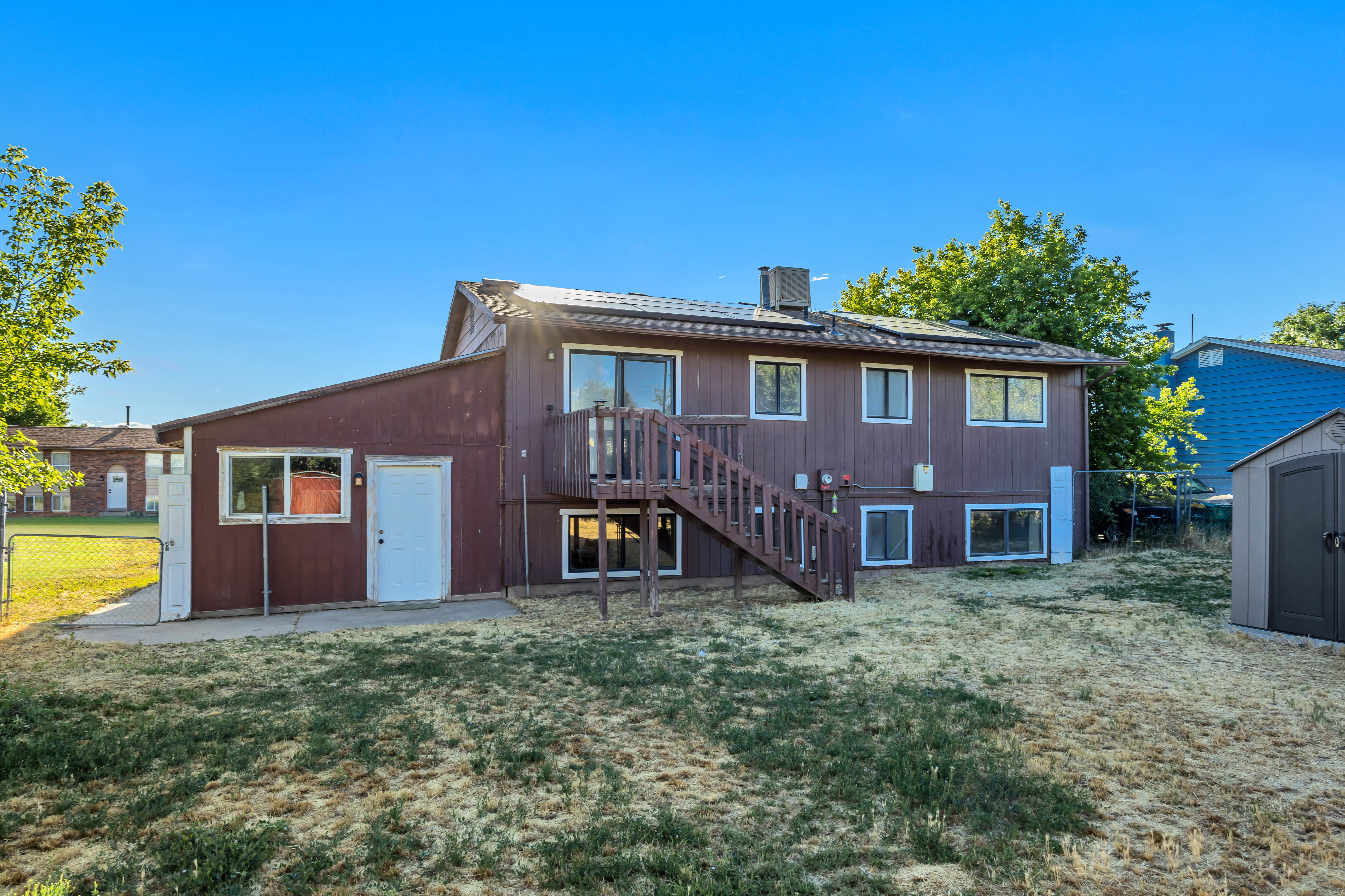 Rear exterior featuring a multi-level structure with brown siding and white trim windows
