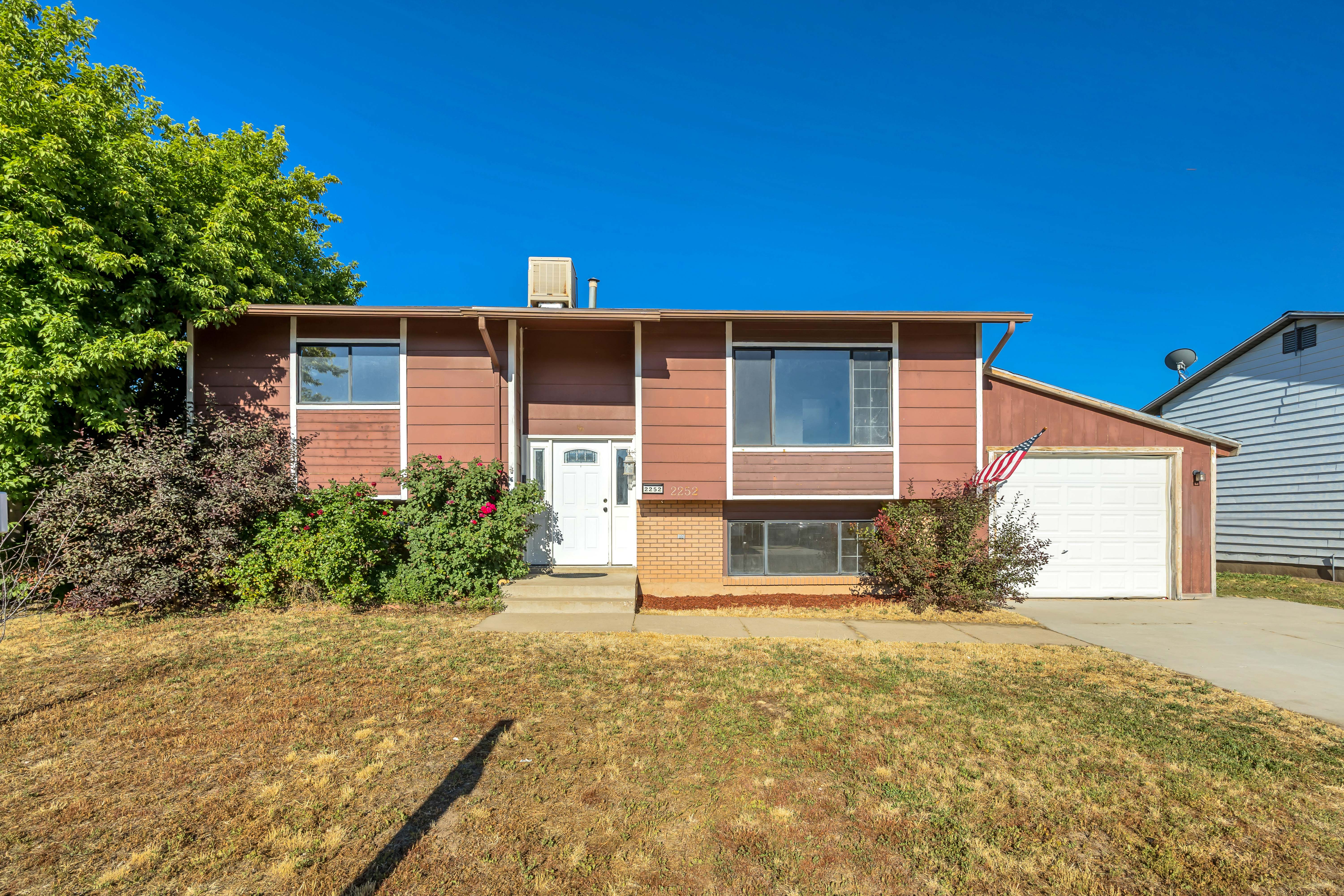Split-level residence featuring a brown siding exterior, white trim accents, and an attached garage with a white door