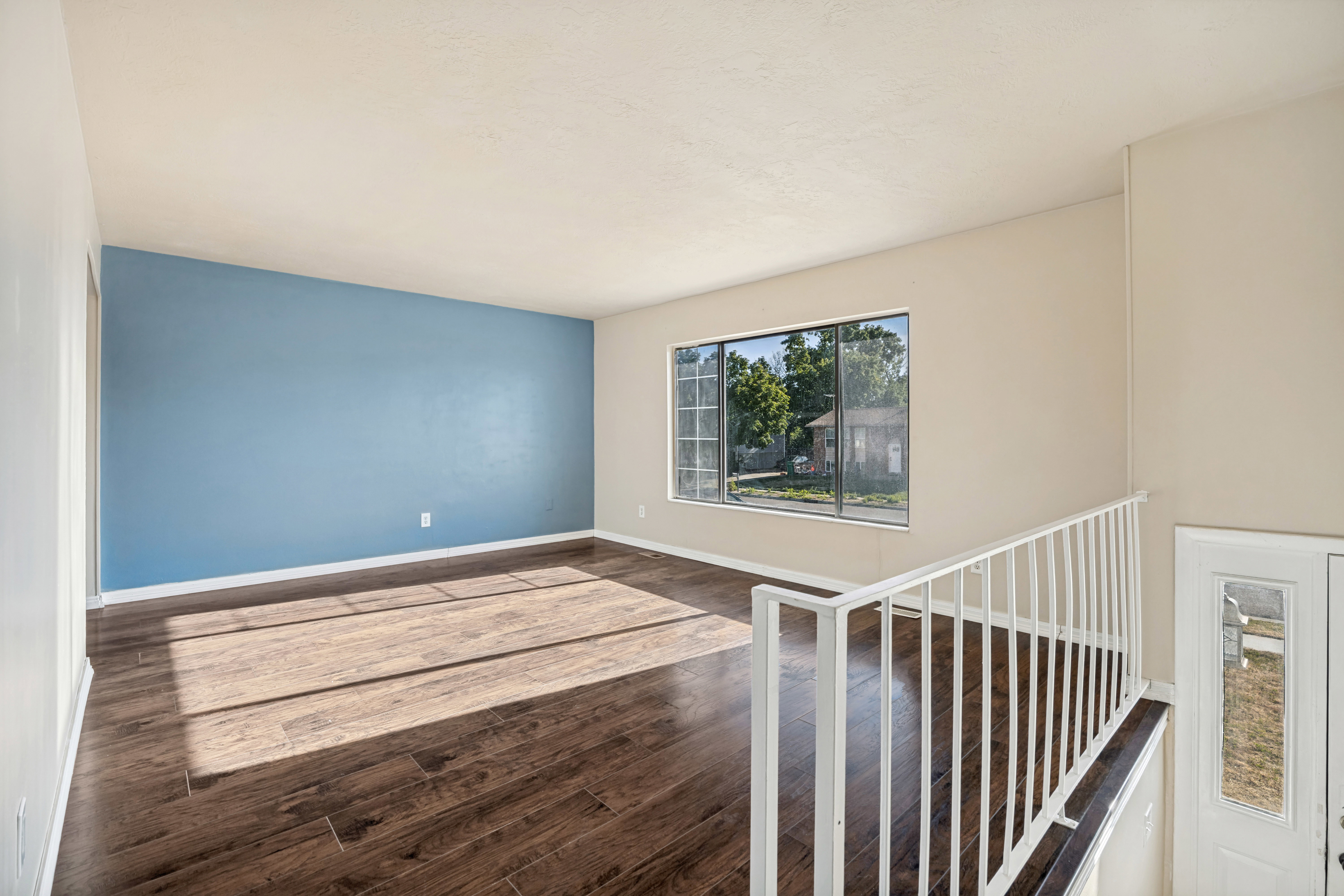 Spacious interior room featuring rich wood-finish flooring and a distinctive accent wall
