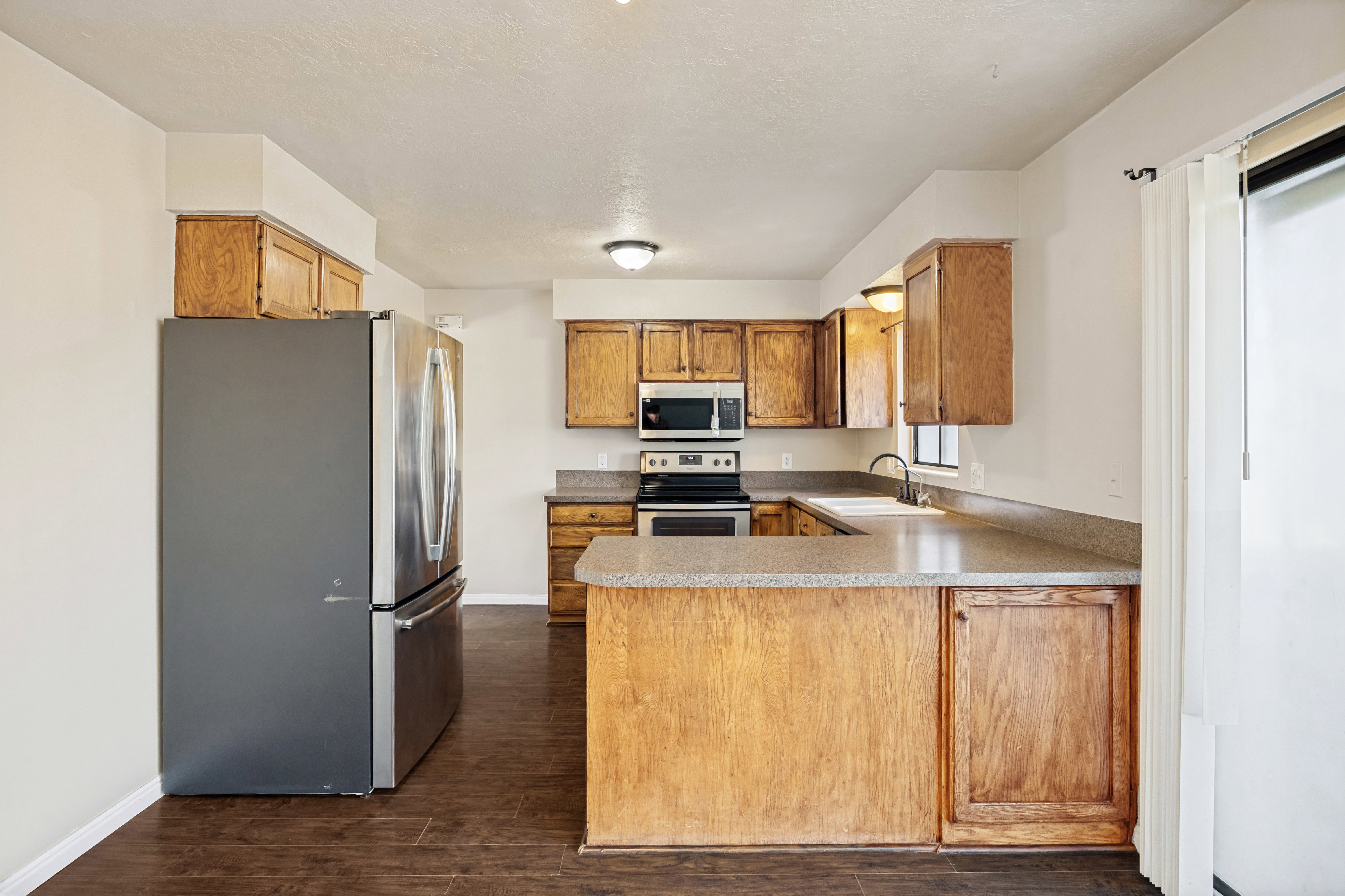Kitchen featuring wood-finish cabinetry, stainless steel appliances, and wood-finish flooring