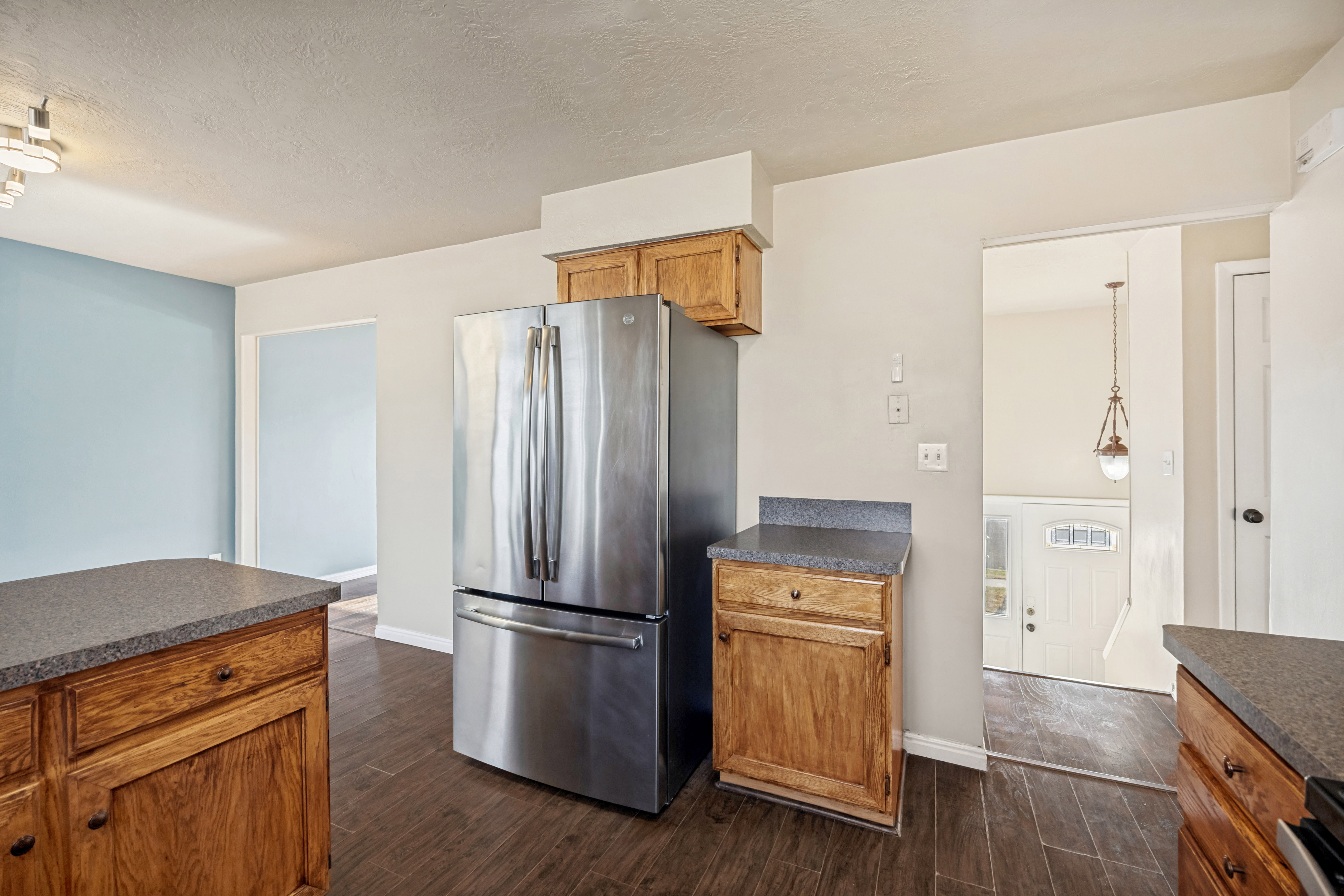 Kitchen featuring wood cabinetry, dark countertops, and wood-finish flooring