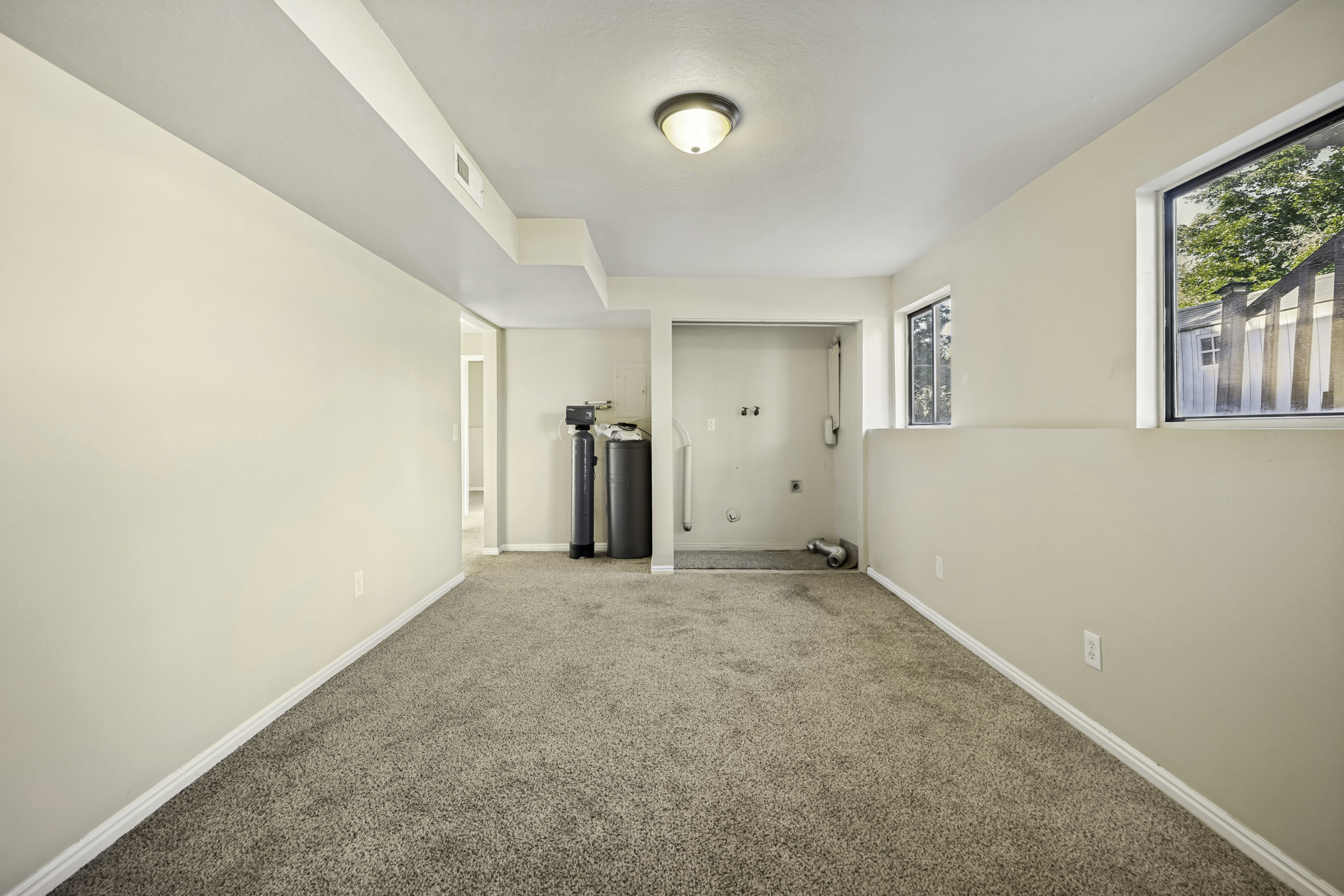 Spacious lower-level room featuring neutral-toned carpeting and light-colored walls