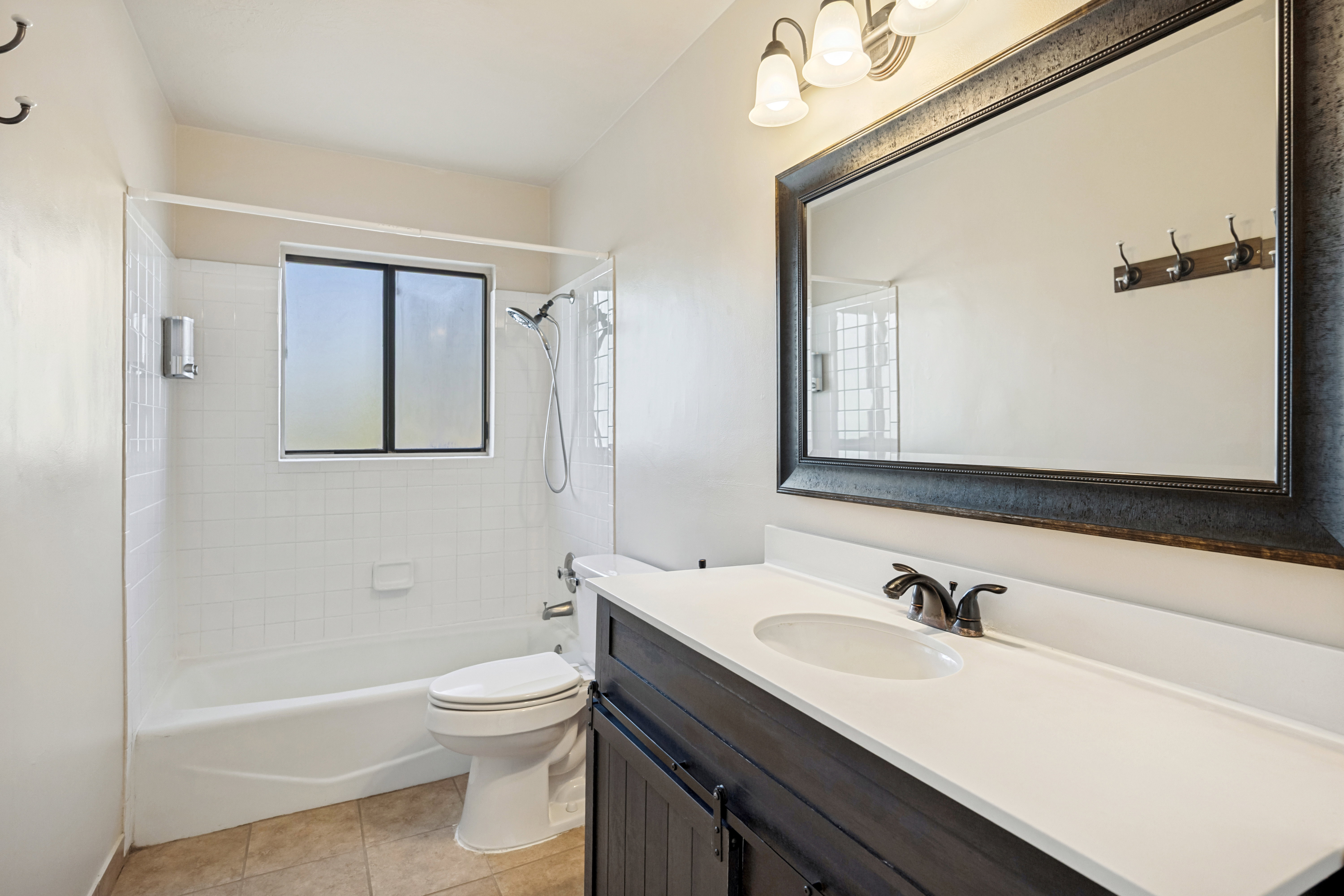 Bathroom featuring a single vanity with a white countertop, dark wood-finish cabinetry, and an oval sink