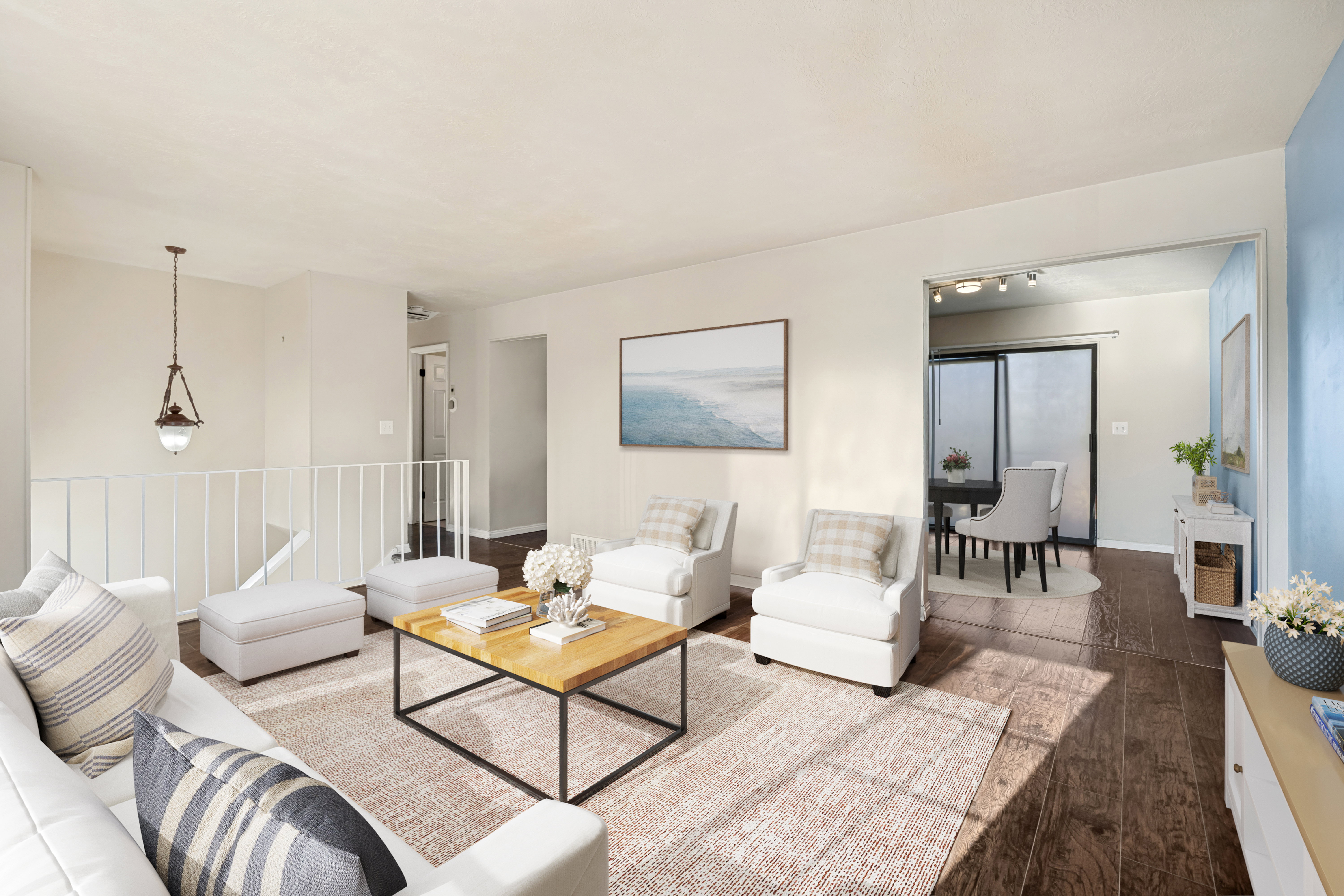 Virtually staged Spacious living area featuring wood-finish flooring, light-toned walls, and an open entryway to another room