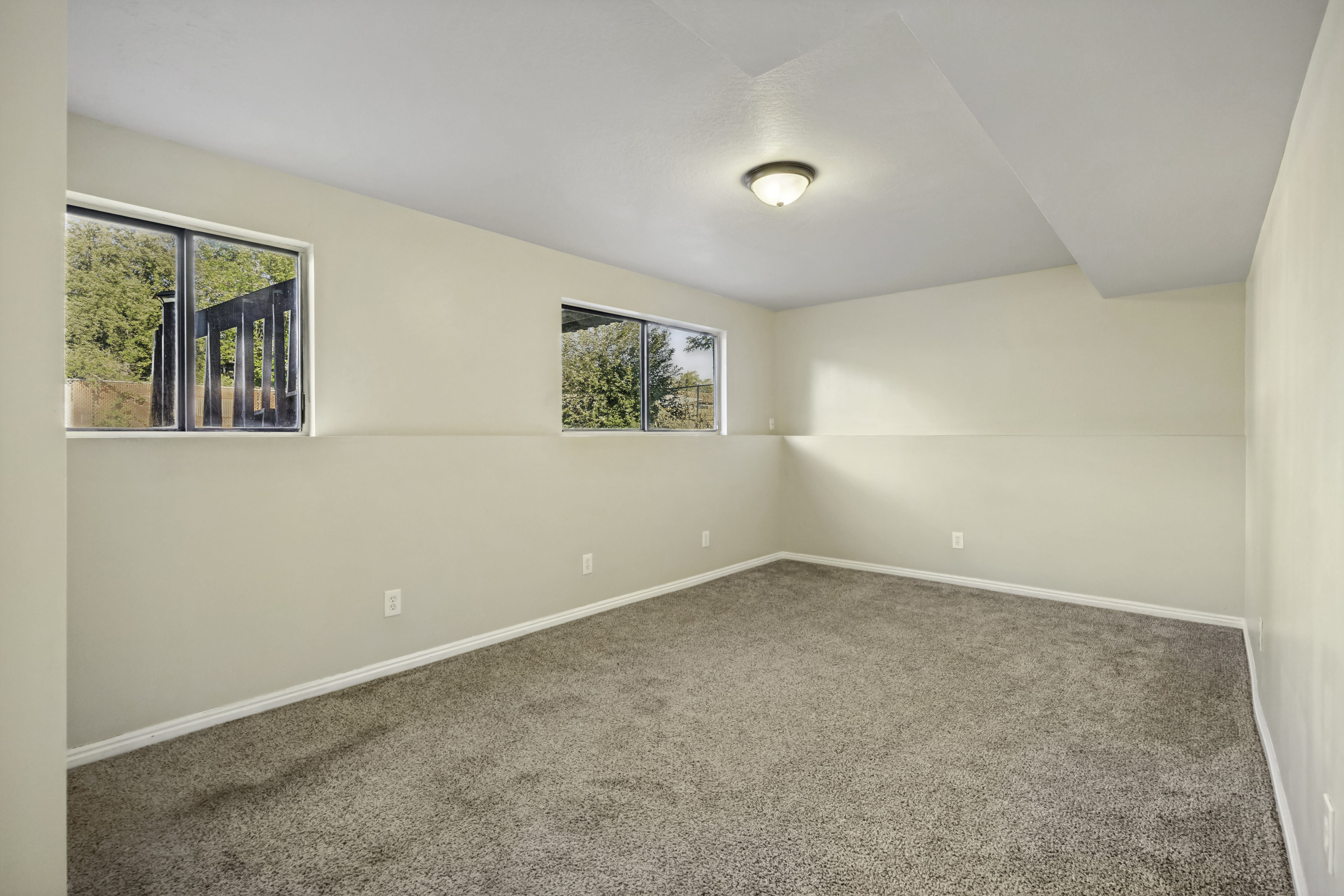 Carpeted room featuring two windows, recessed ceiling, and a flush-mount light fixture