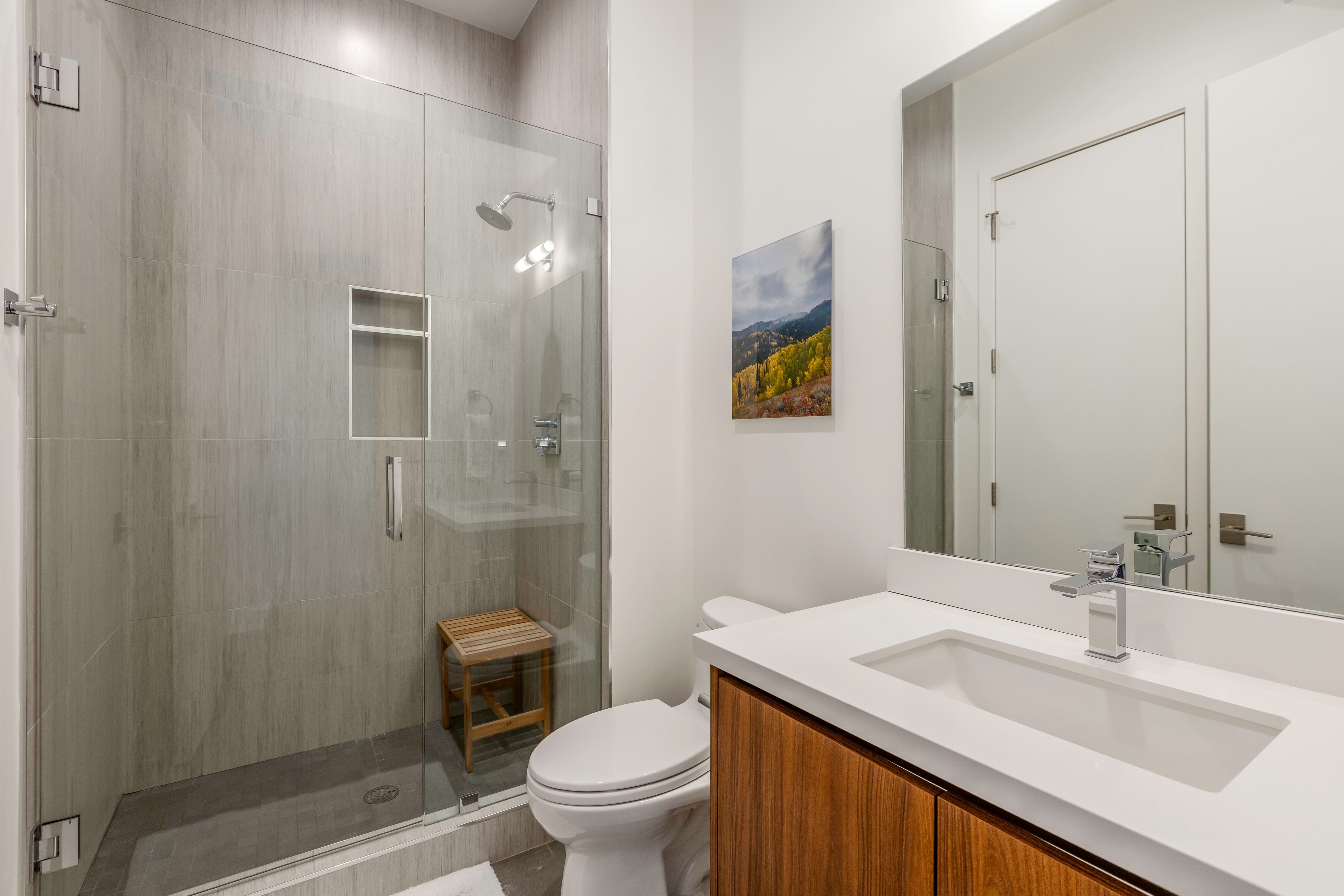 Modern bathroom featuring a glass-enclosed shower with full-height tile surround and a built-in niche