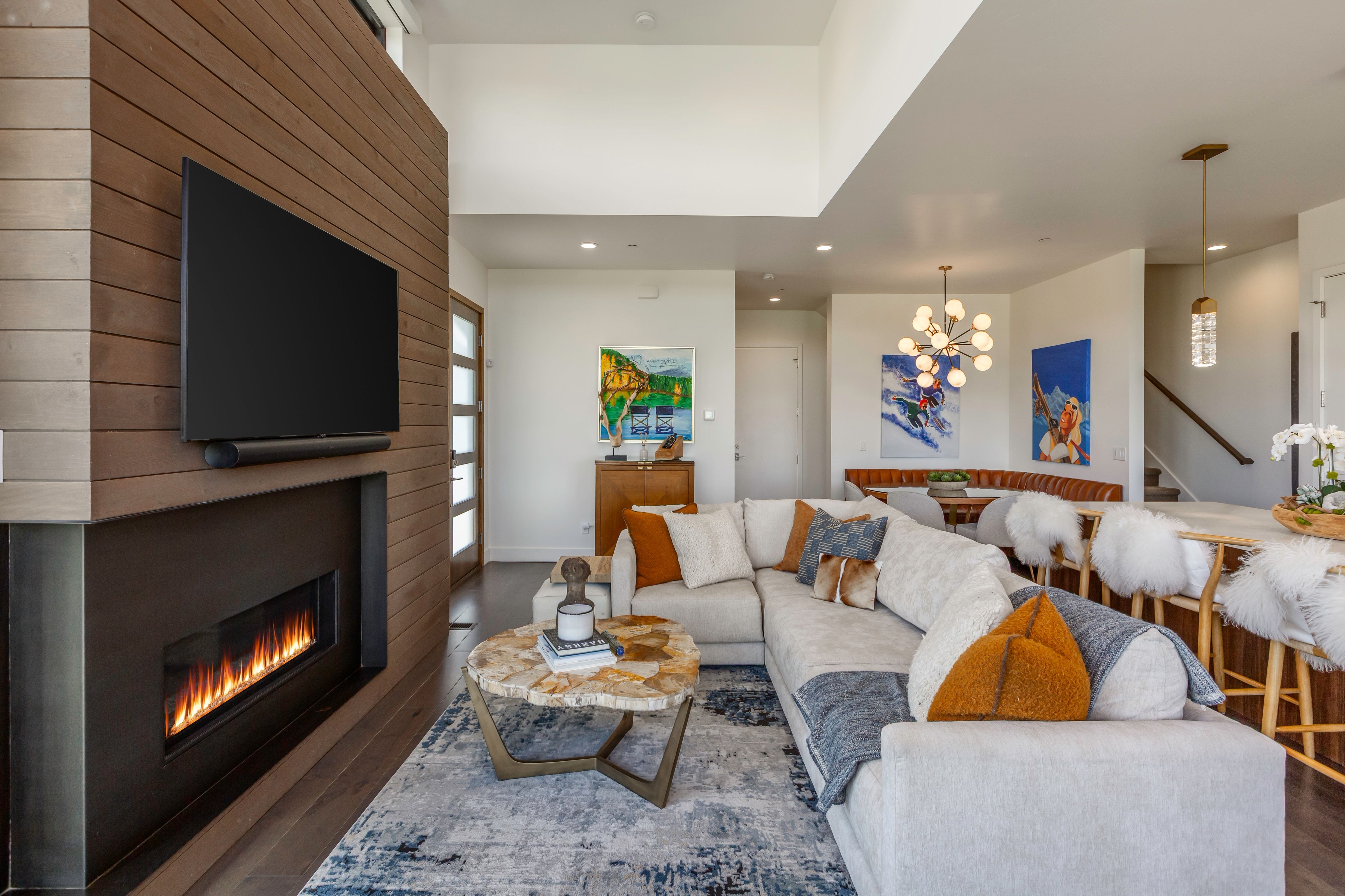 Open-concept living area featuring a wood-panel accent wall with an integrated linear fireplace