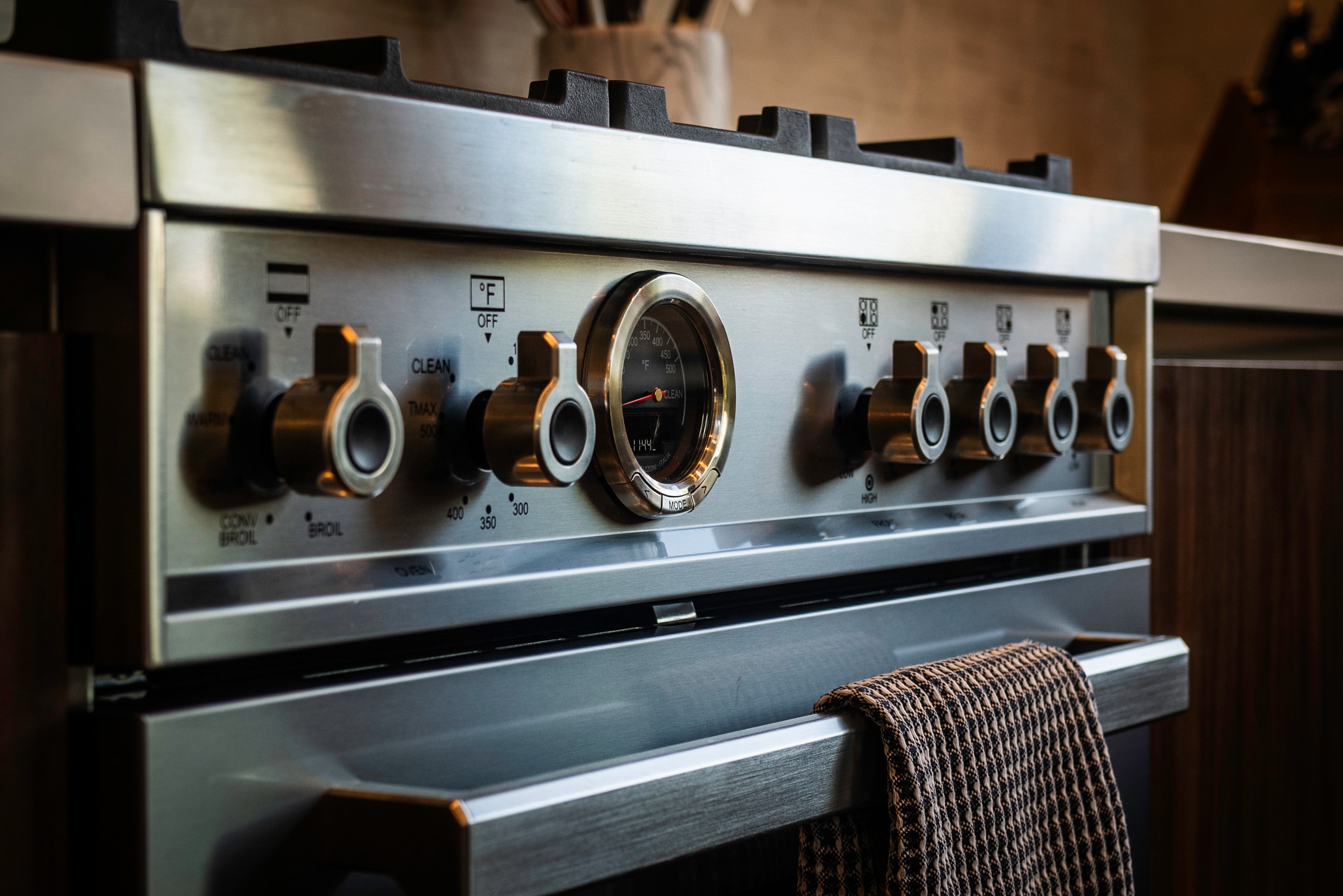 Stainless steel range with metallic knobs and integrated oven temperature gauge