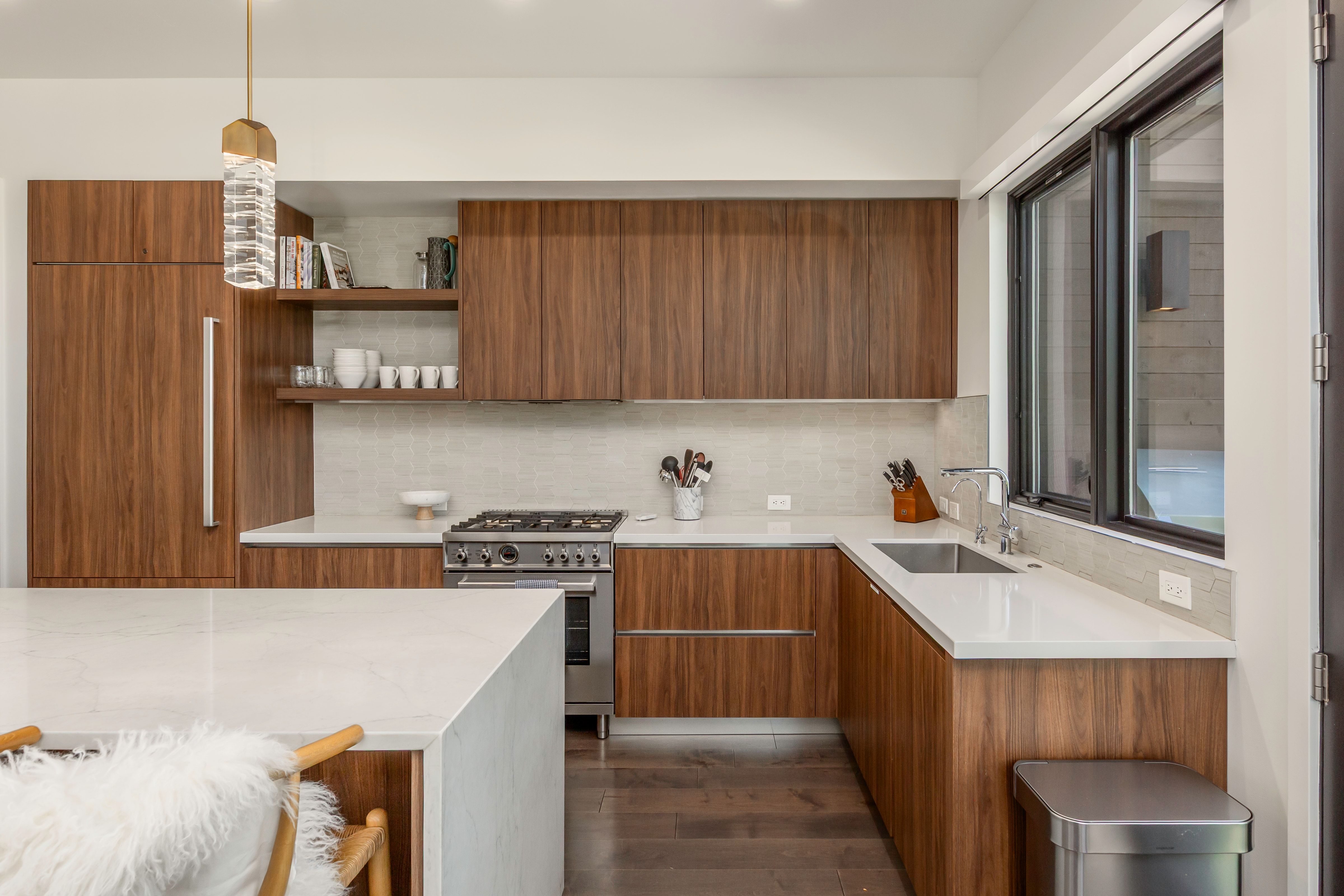 Modern kitchen featuring wood-finish cabinetry, light countertops, and a stainless steel range
