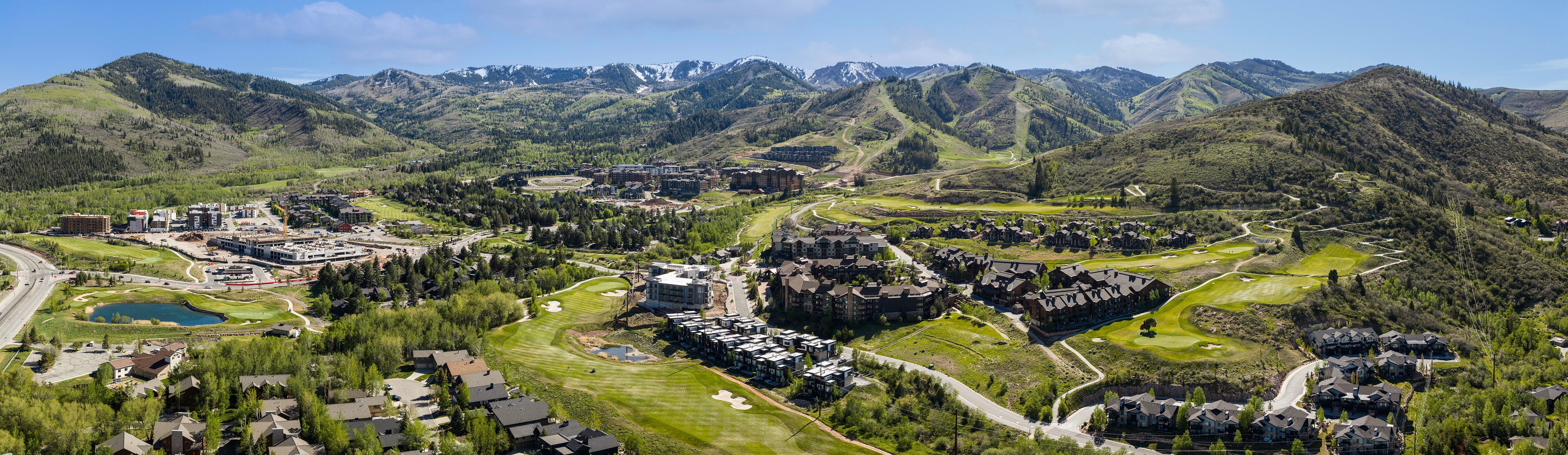 Expansive mountain landscape featuring varied terrain, a winding road, and multiple residential and commercial structures