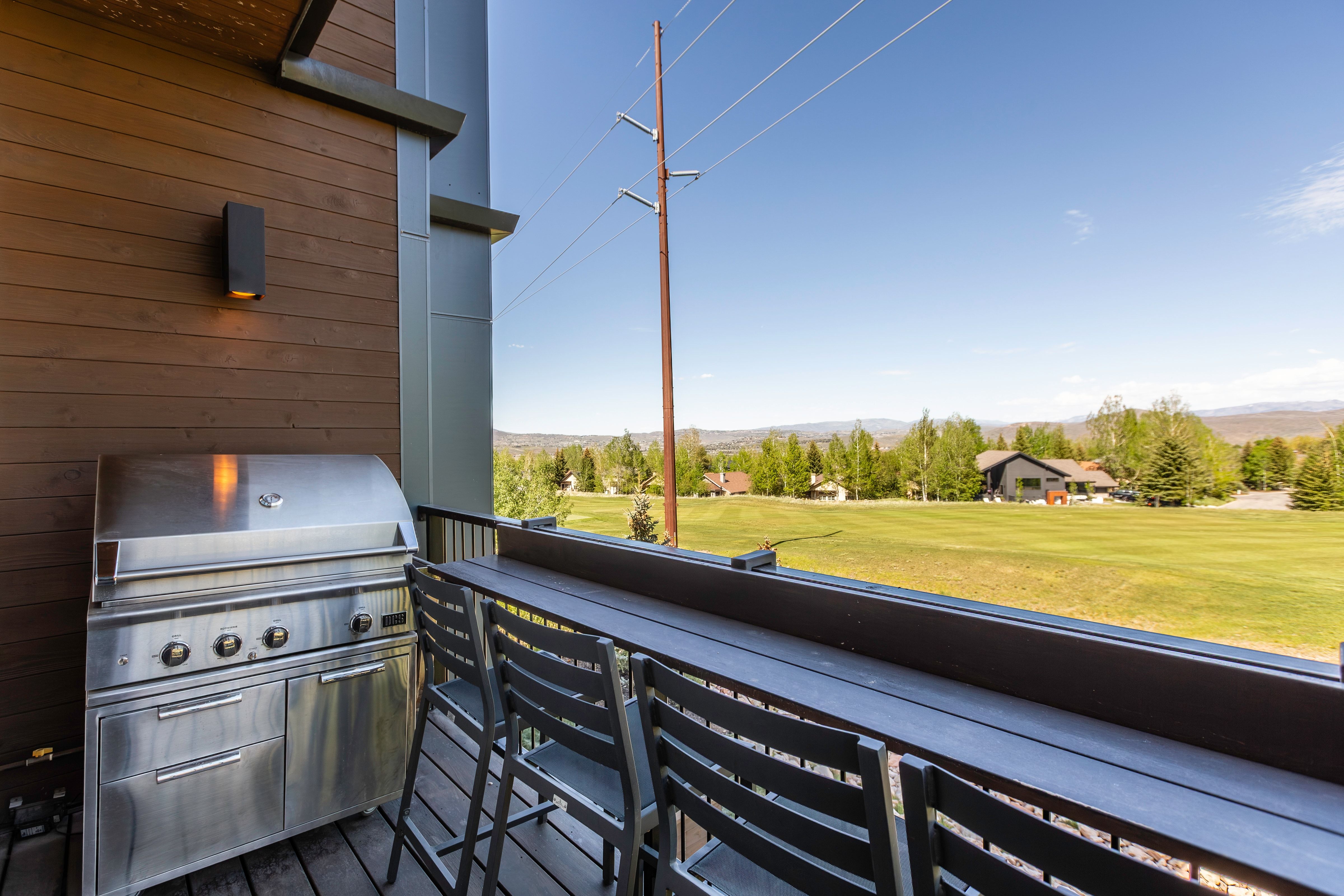 Exterior balcony featuring wood-finish siding, a stainless steel grill, a built-in counter-height table, and metal railings
