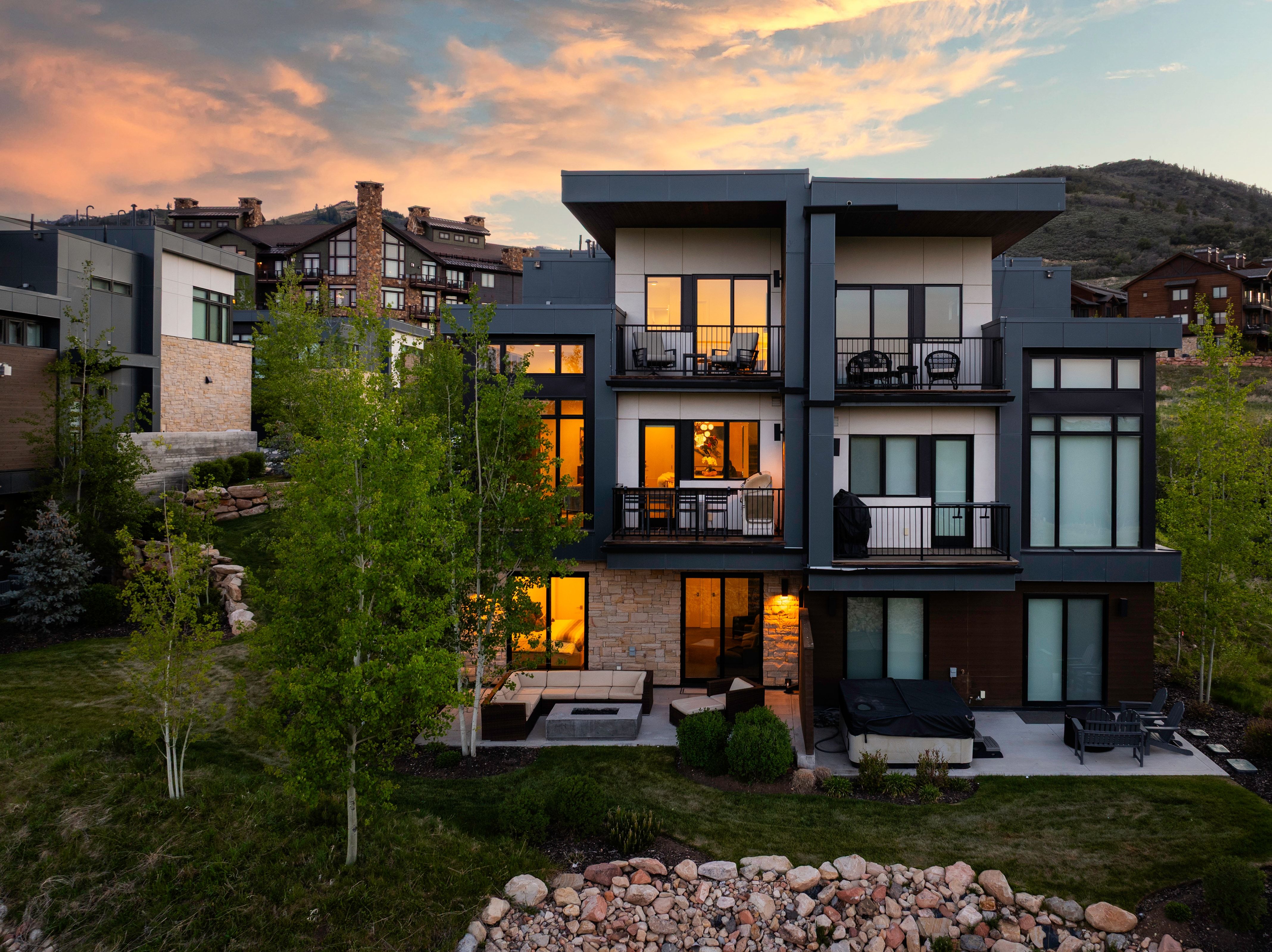 Contemporary multi-level residence featuring dark gray and white exterior siding with stone accents