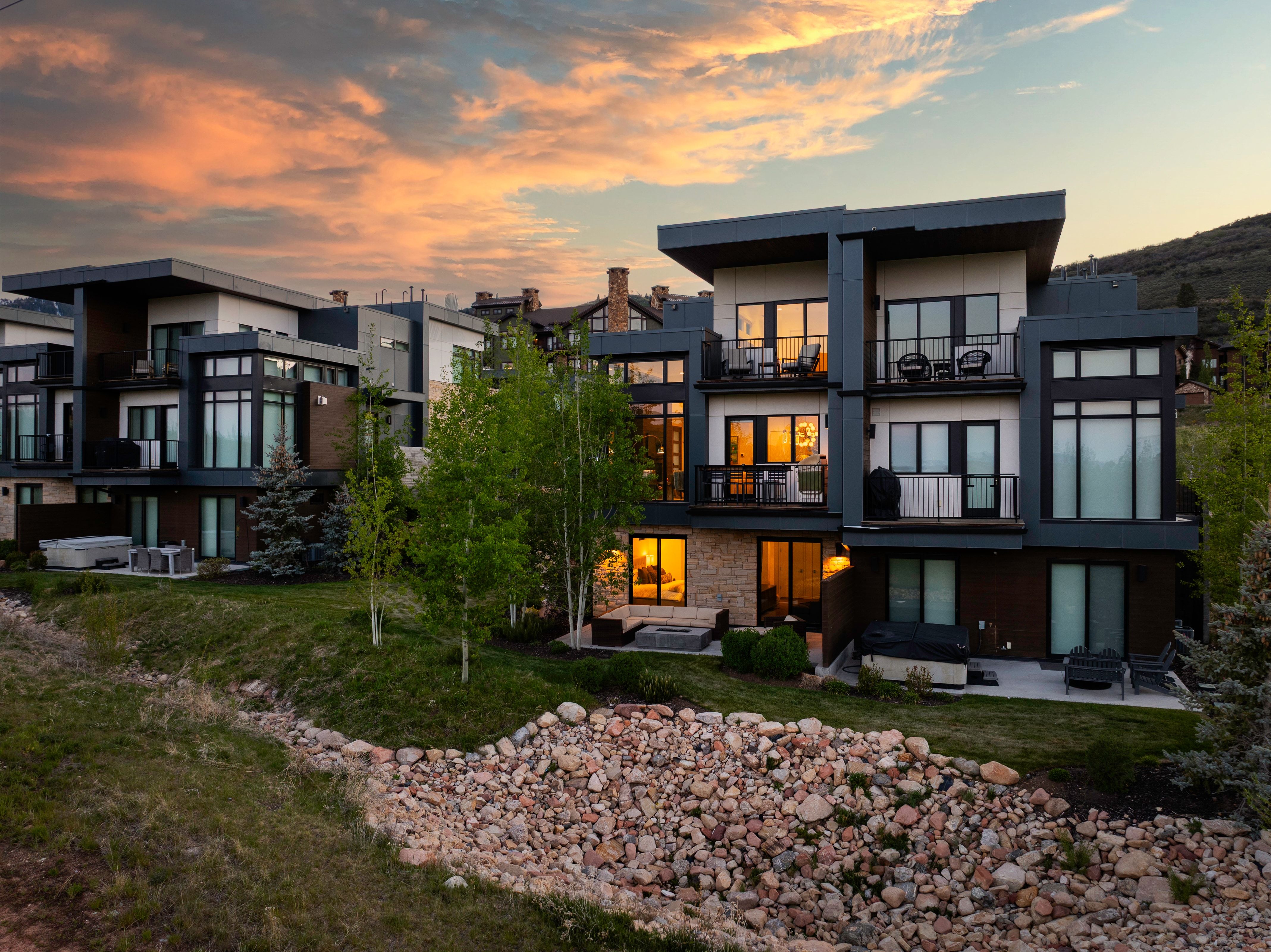 Contemporary multi-level residences featuring expansive windows, private balconies with metal railings, and a mix of white siding and dark paneling