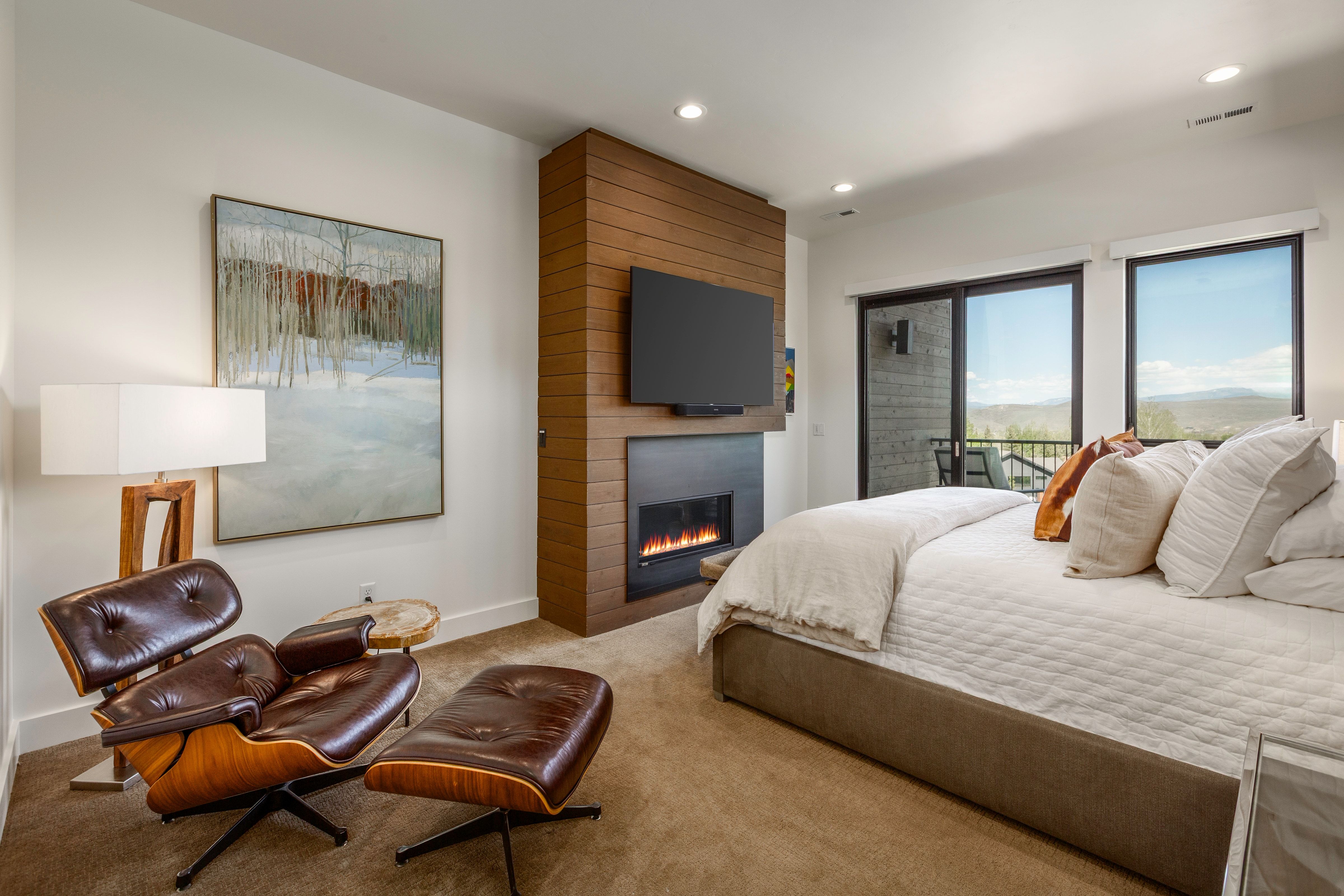 Bedroom featuring a recessed fireplace with a wood-finish accent wall, ceiling-mounted lighting, and a glass sliding door opening to an exterior space