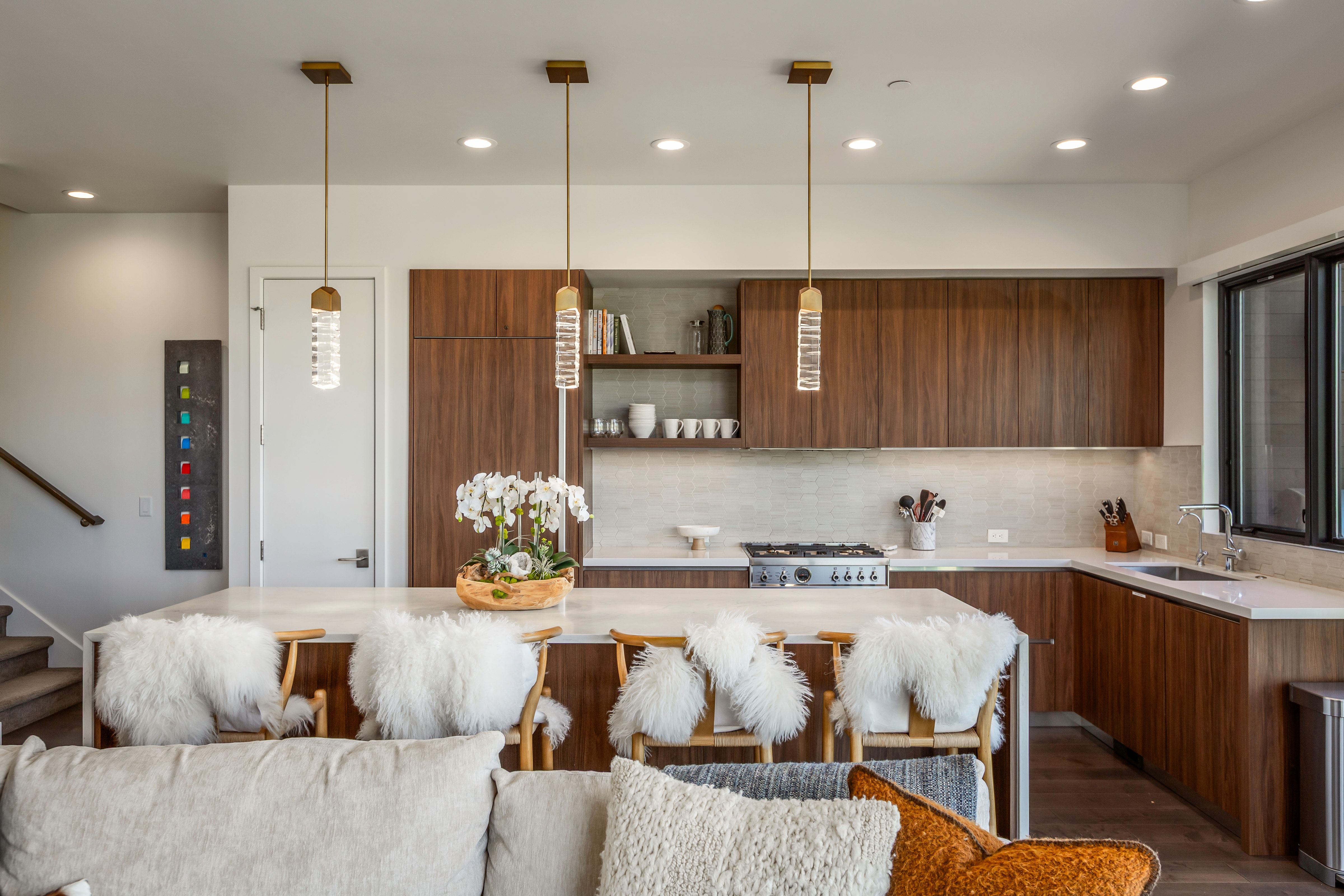 Open-concept kitchen featuring an oversized island with seating, dark wood-finish cabinetry, a stainless steel gas range, and recessed lighting
