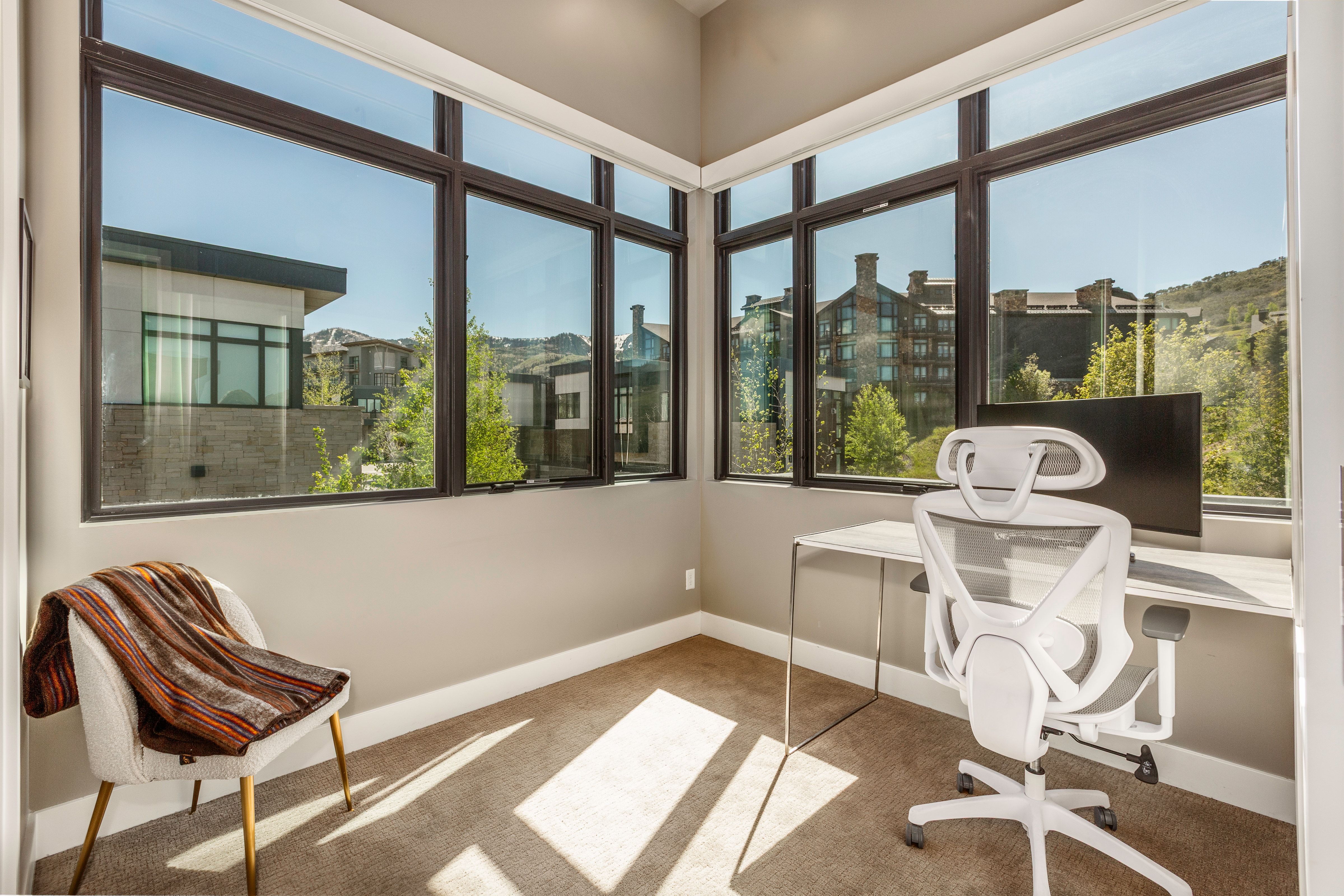 Corner room featuring expansive windows with dark framing, neutral wall paint, and carpeting