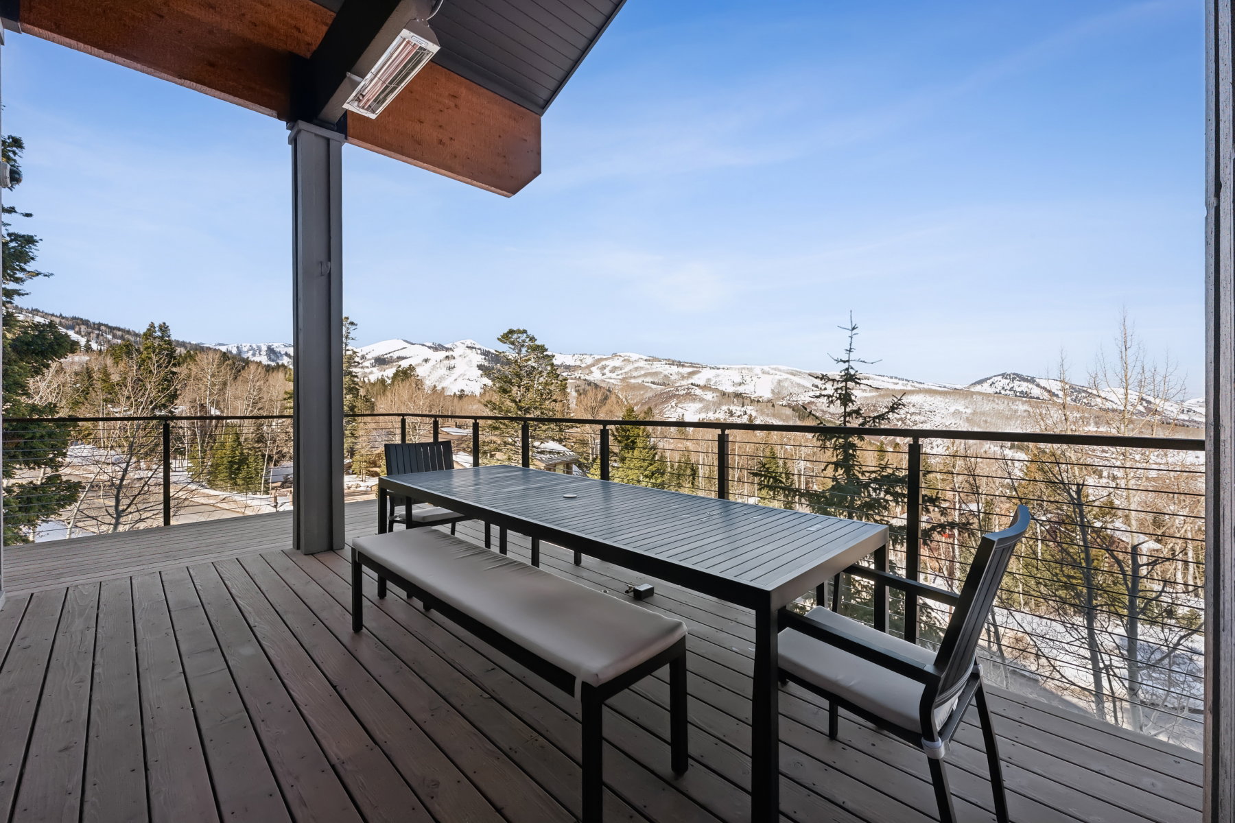 Expansive outdoor deck featuring composite decking, a cable railing system, and a wood-paneled ceiling with an integrated overhead heater
